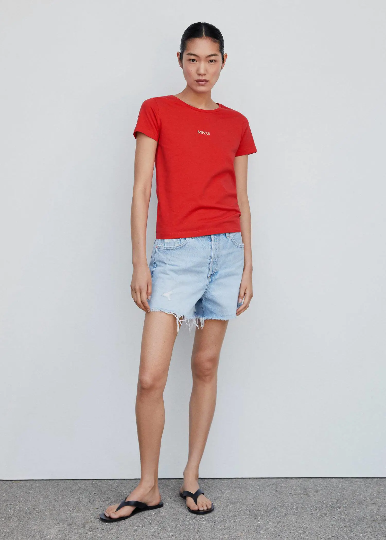 Mango Metallic logo T-shirt. a woman in red shirt and blue jean shorts. 