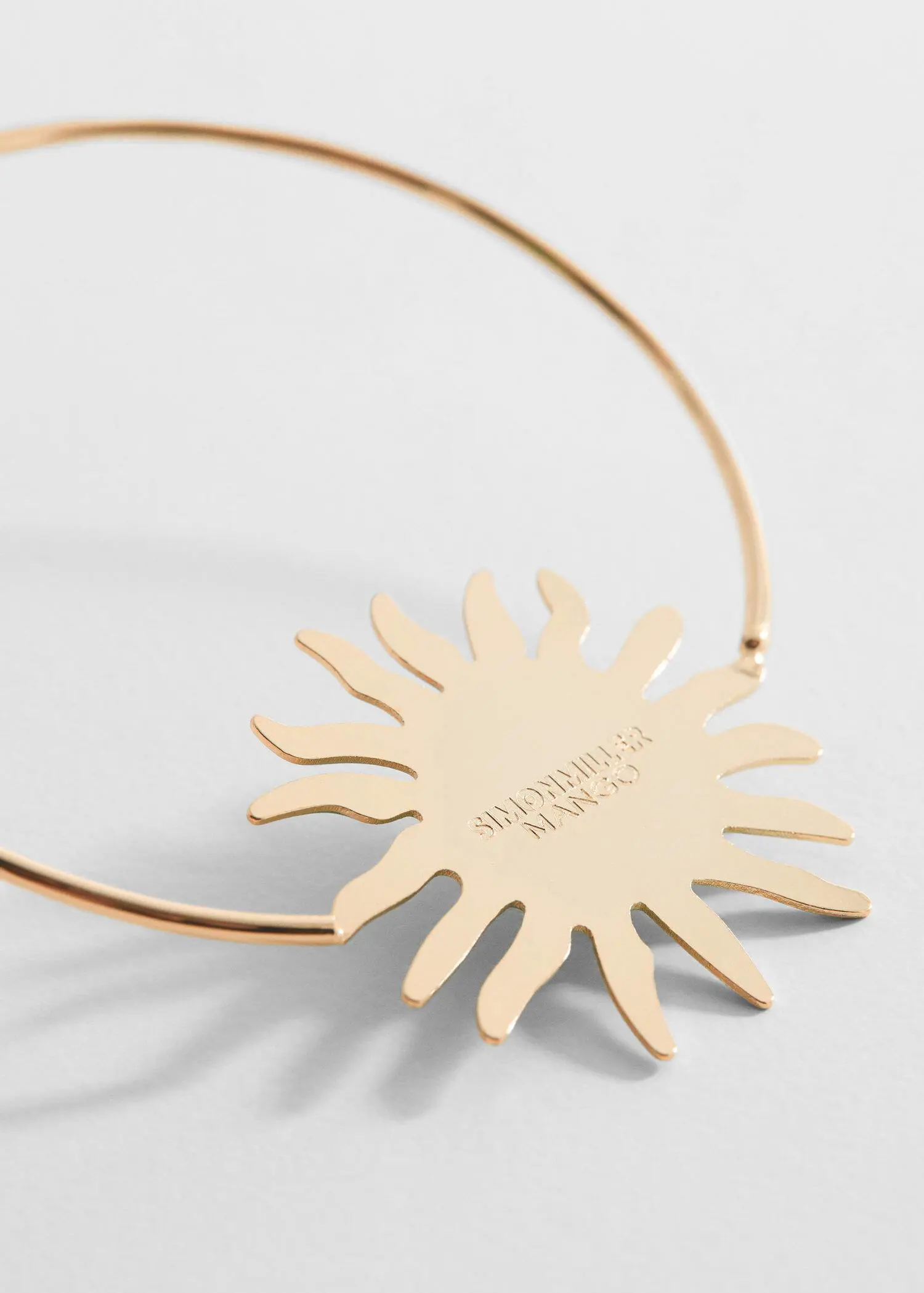 Mango Maxi hoop earrings. a close-up of a necklace that is shaped like a sun. 