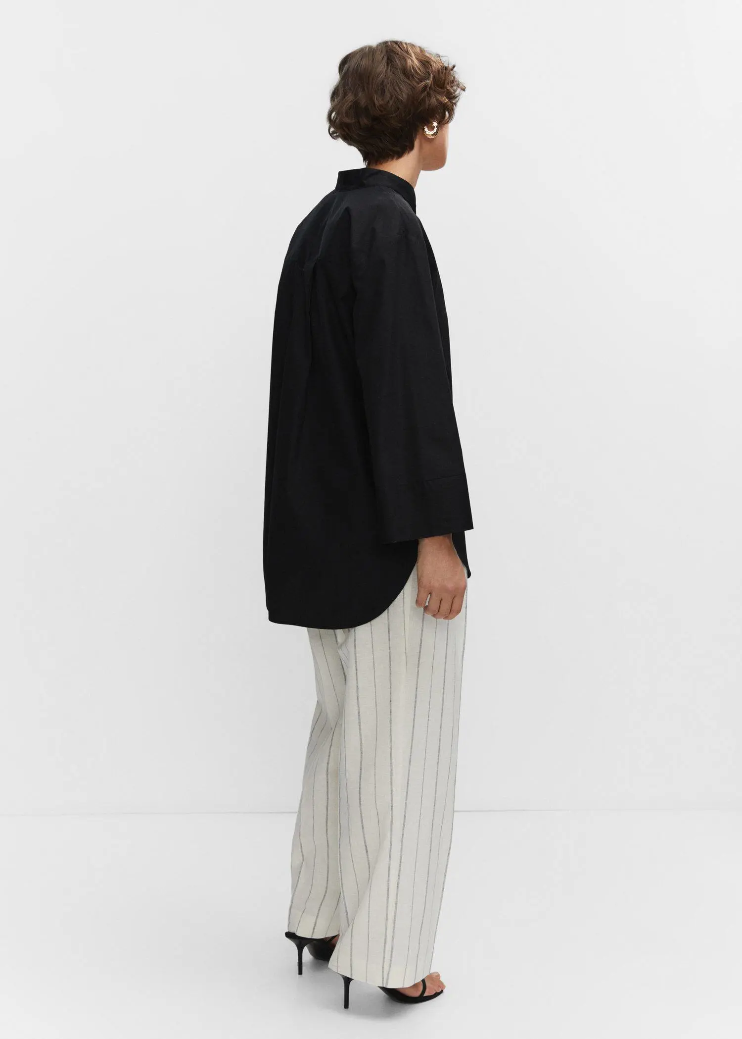 Mango Oversized V-neck blouse. a person standing in front of a white wall. 