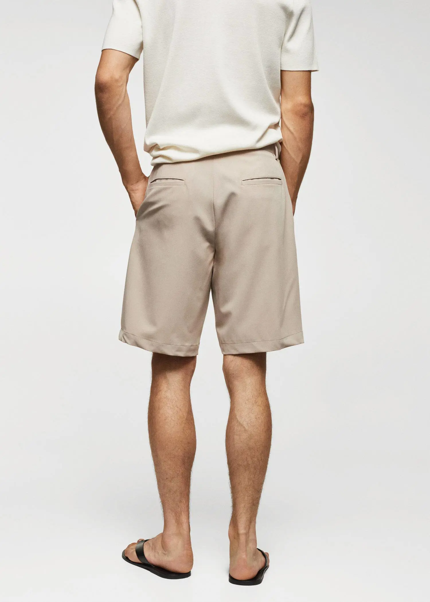 Mango Cotton pleated Bermuda shorts. a man standing with his hands in his pockets. 