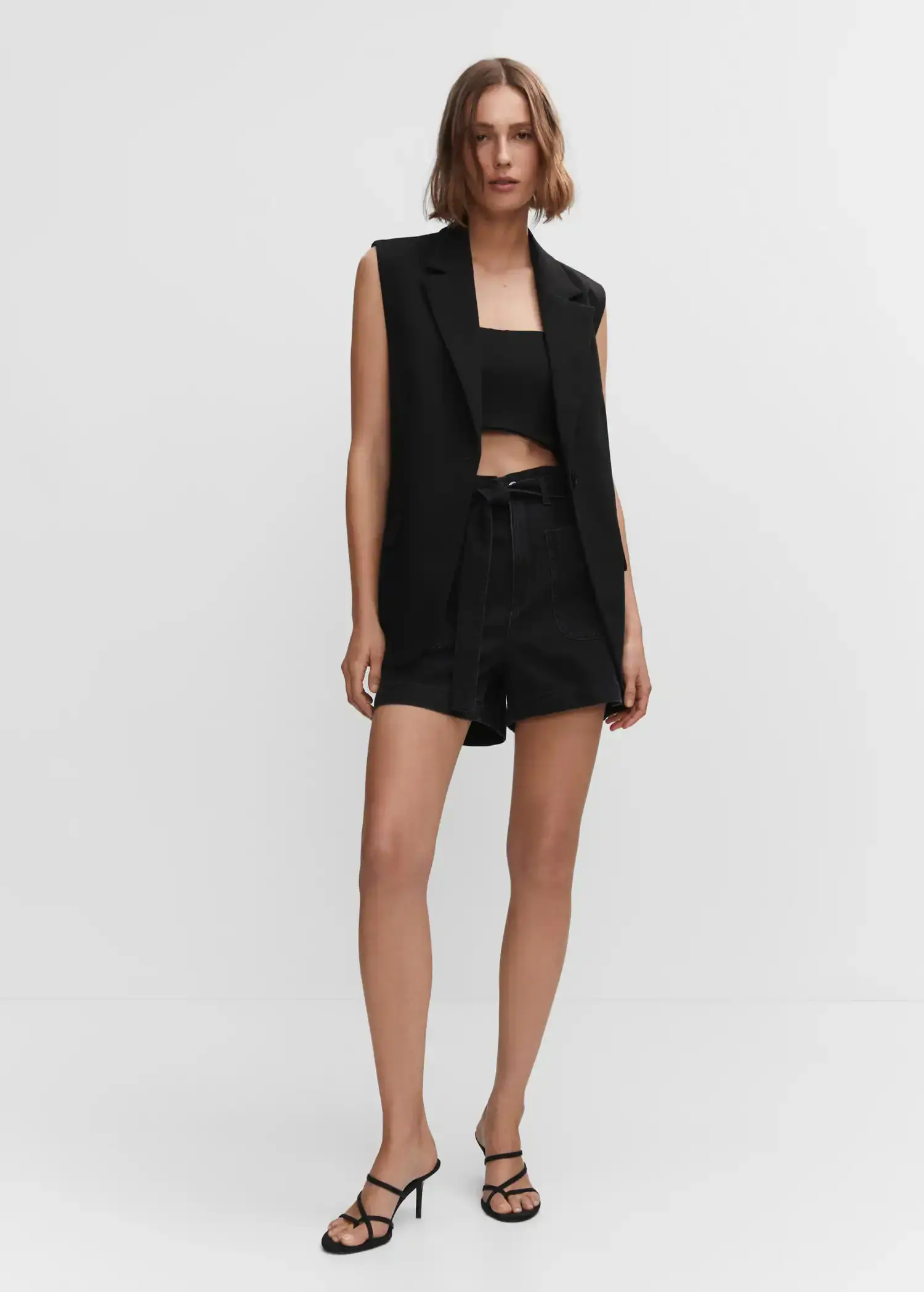 Mango Paperbag shorts with belt. a woman in a black outfit is posing for a picture. 