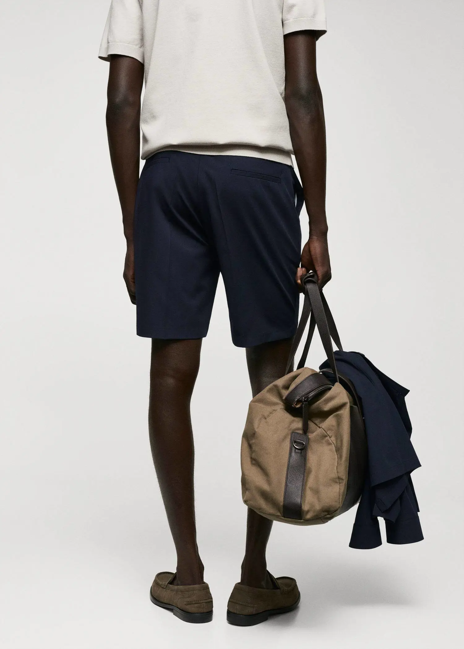 Mango Slim-fit bermuda shorts with adjustable waist. a man holding a bag in his hand. 