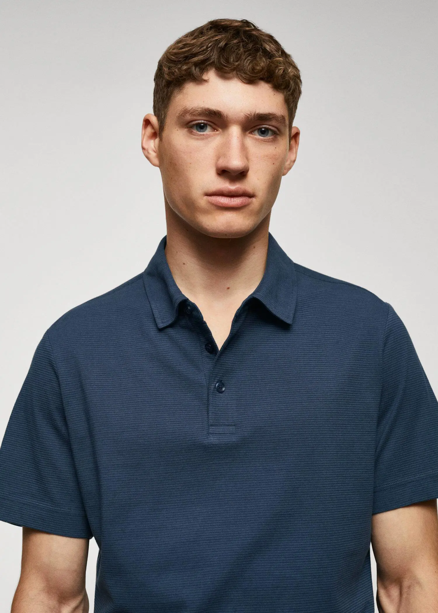 Mango 100% cotton polo shirt with striped structure. a young man wearing a blue polo shirt. 