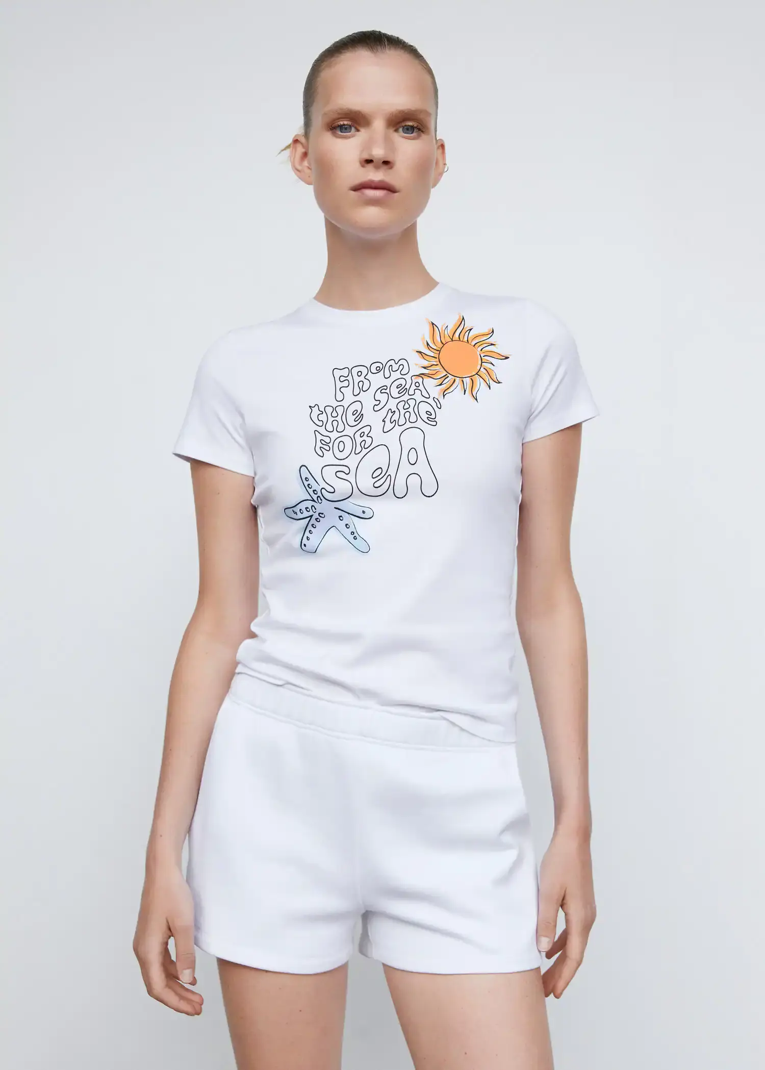 Mango Oceans Day T-shirt. a woman wearing a white t-shirt and shorts. 