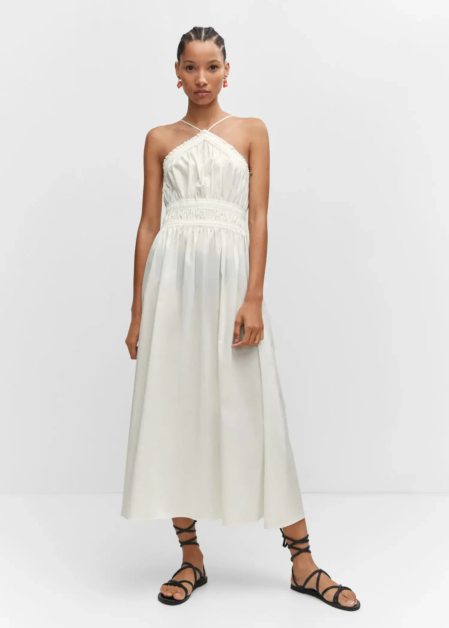 Mango Halter-neck dress with ruffle details. a woman wearing a white dress standing in a room. 