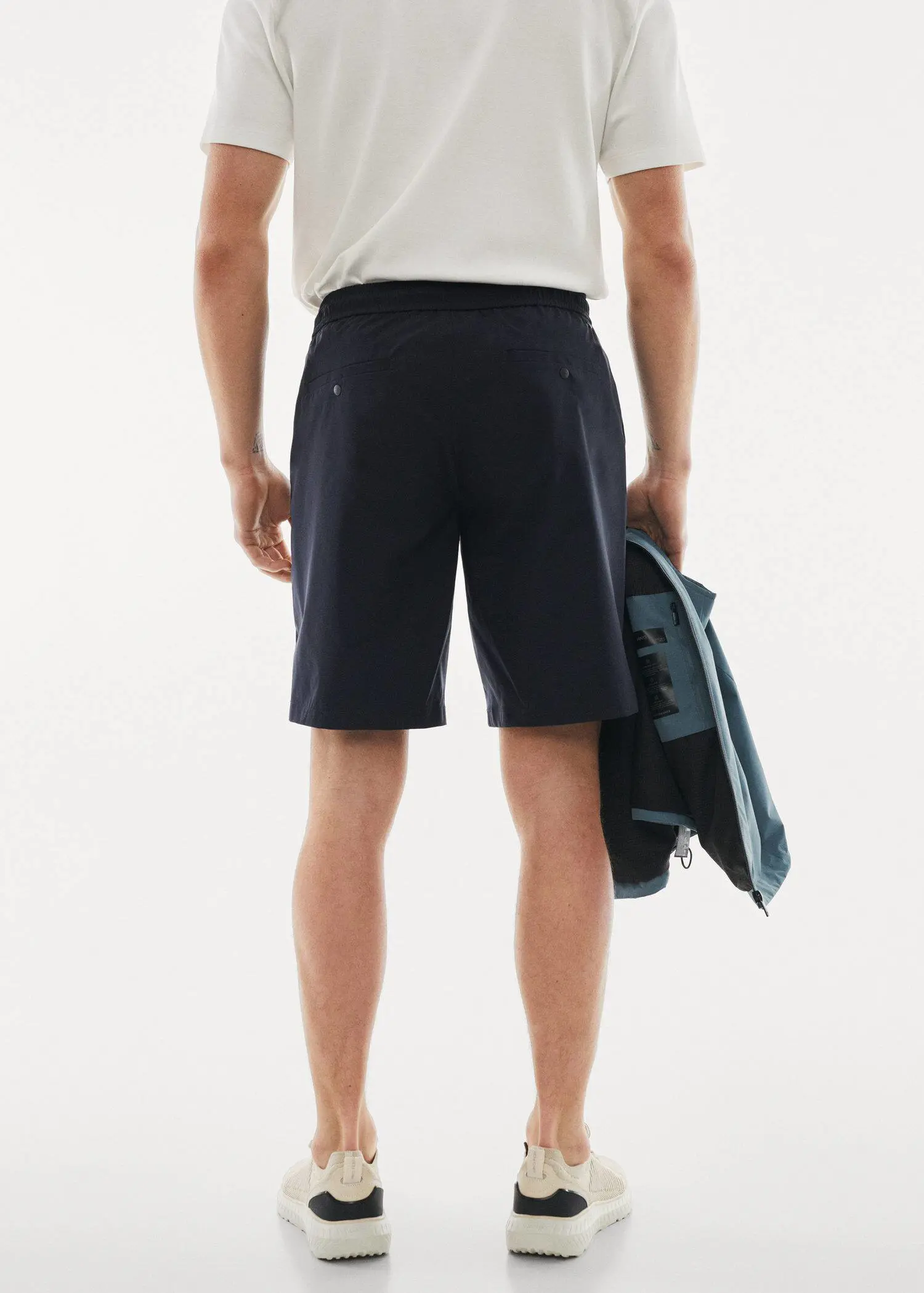 Mango Technical fabric bermuda shorts with drawstring. a man holding a surfboard while standing in front of a wall. 