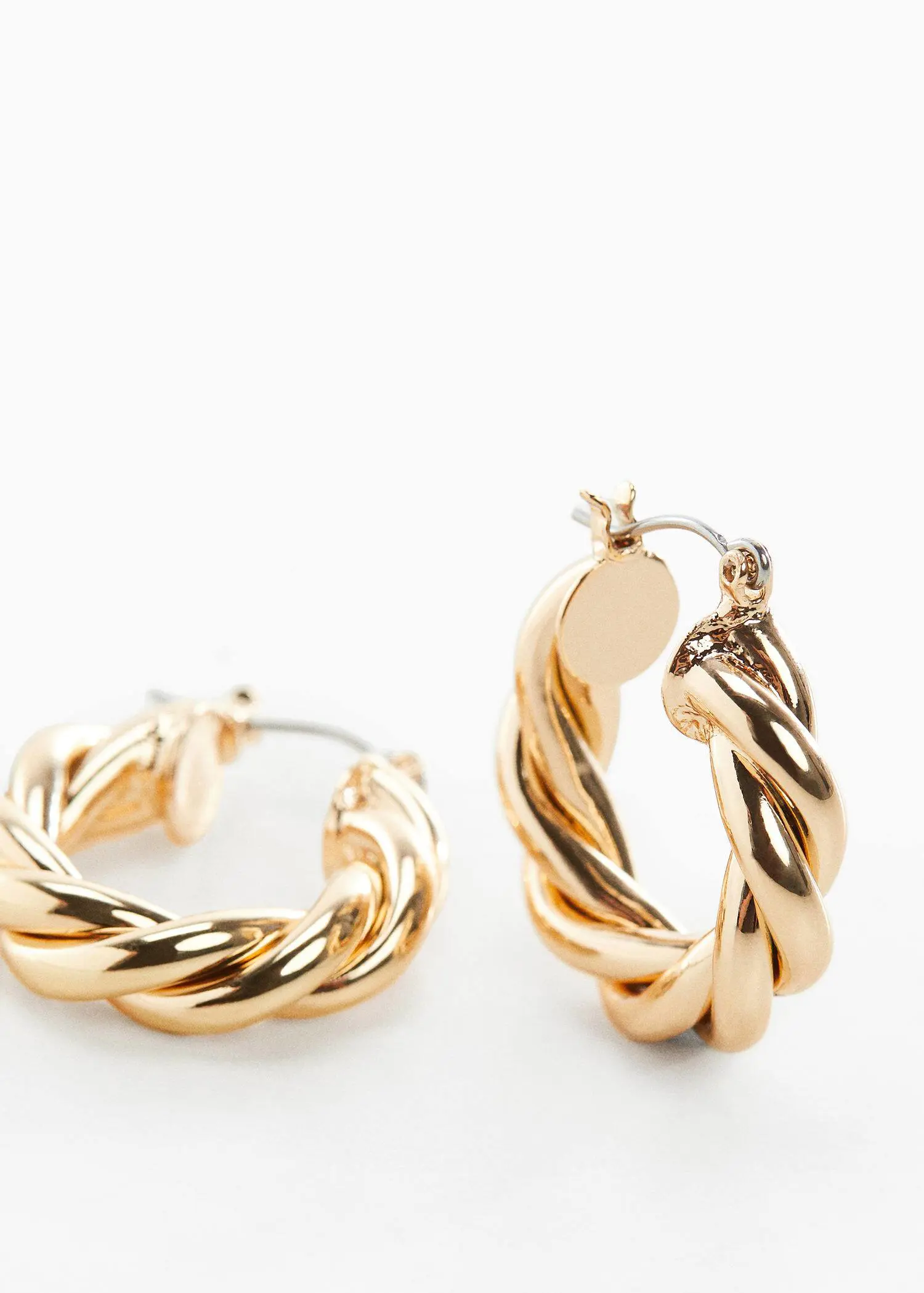 Mango Intertwined hoop earrings. a close up of a pair of gold earrings 