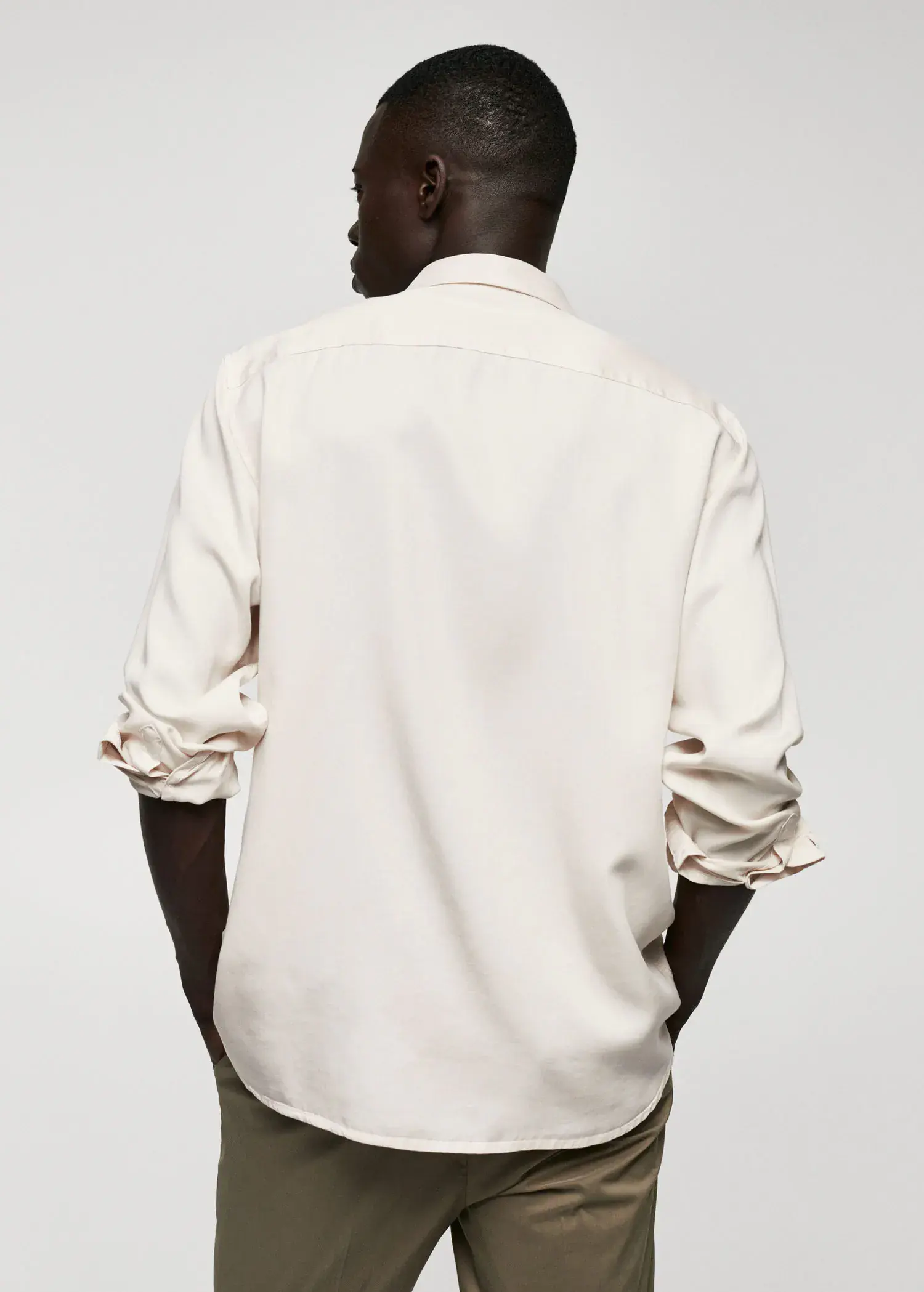 Mango Lyocell fluid shirt. a man in a white shirt is standing with his hands in his pockets. 