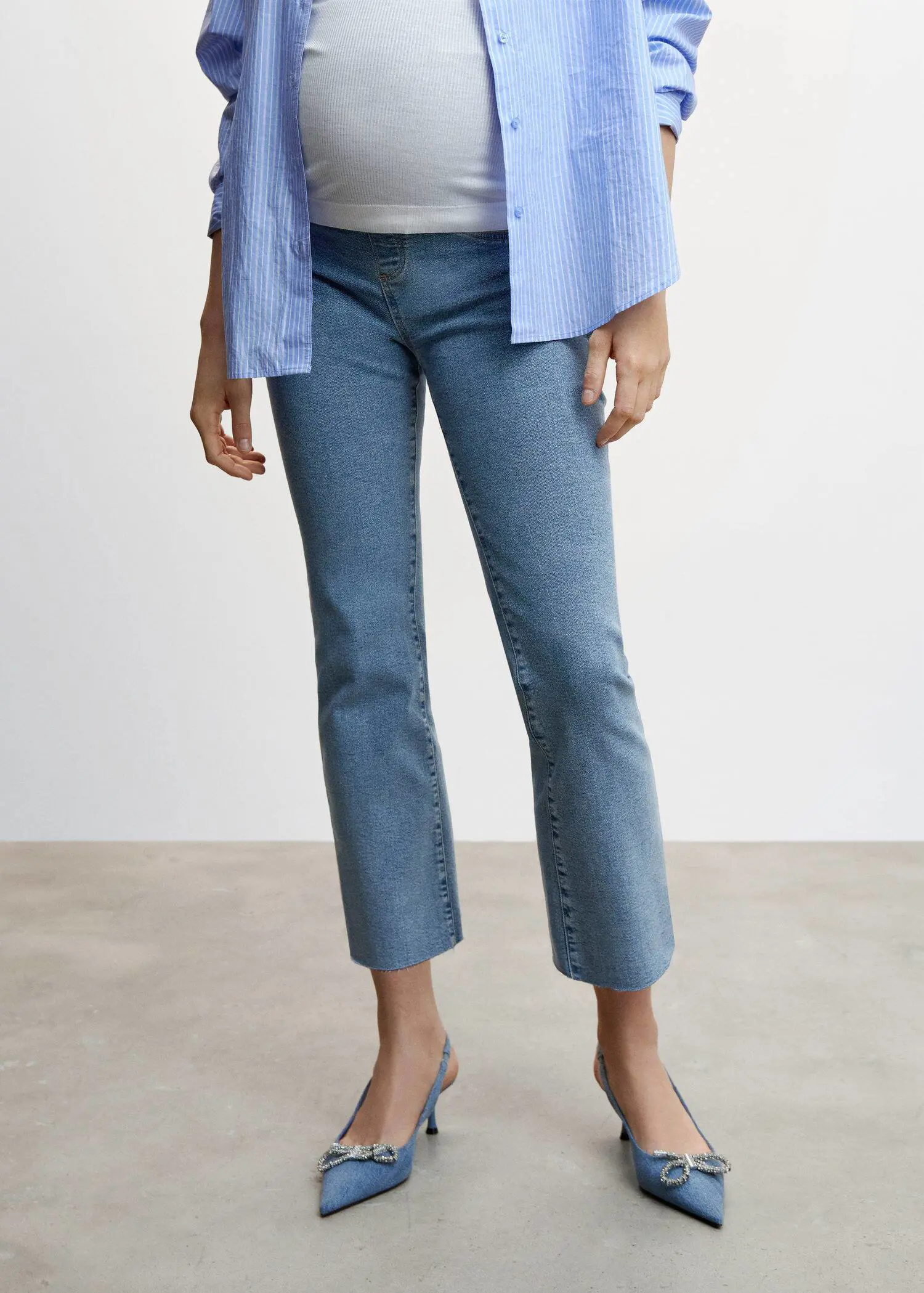 Mango Maternity flared cropped jeans. a person standing in front of a white wall. 