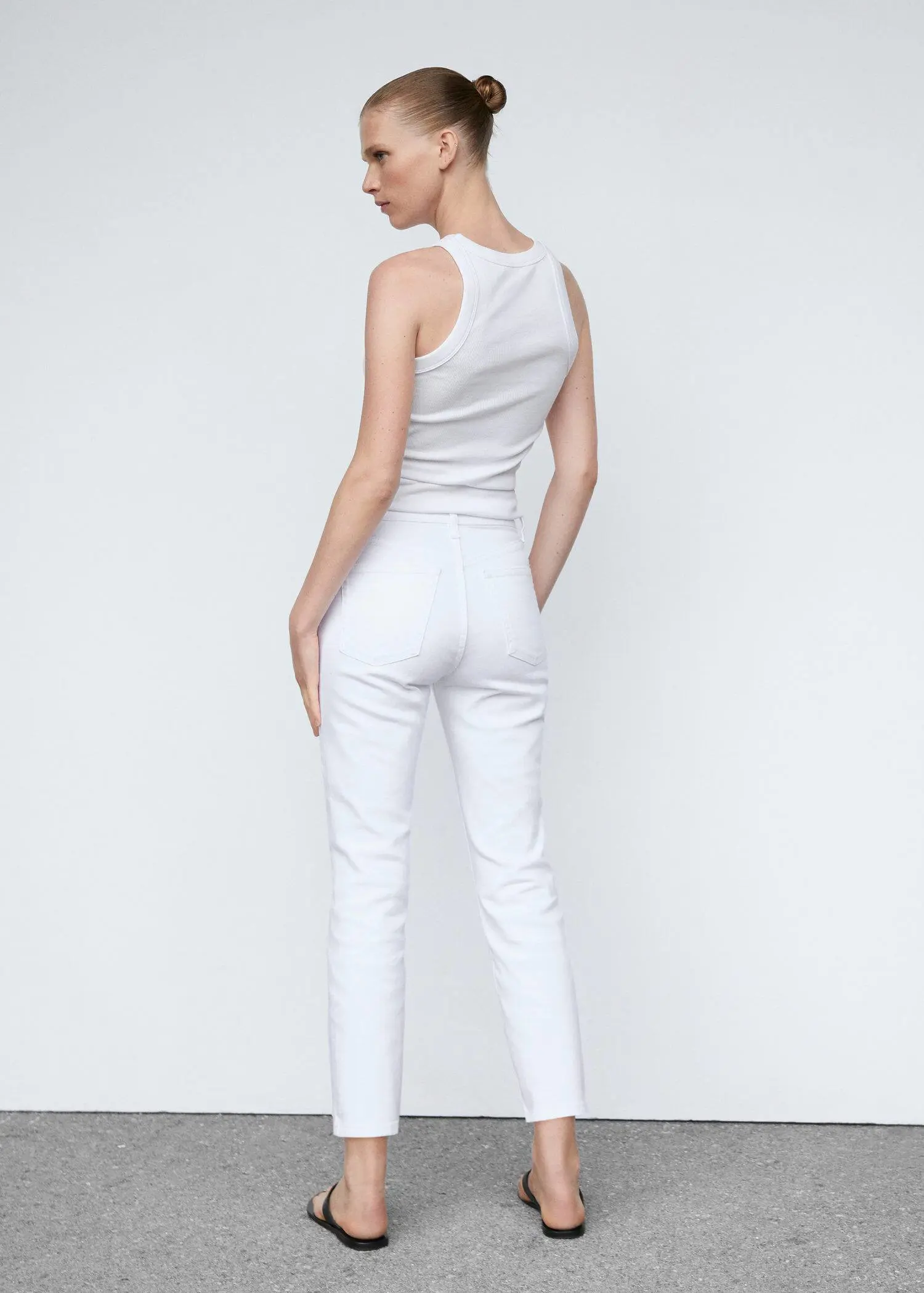 Mango Slim cropped jeans. a woman wearing all white is standing in front of a white wall. 