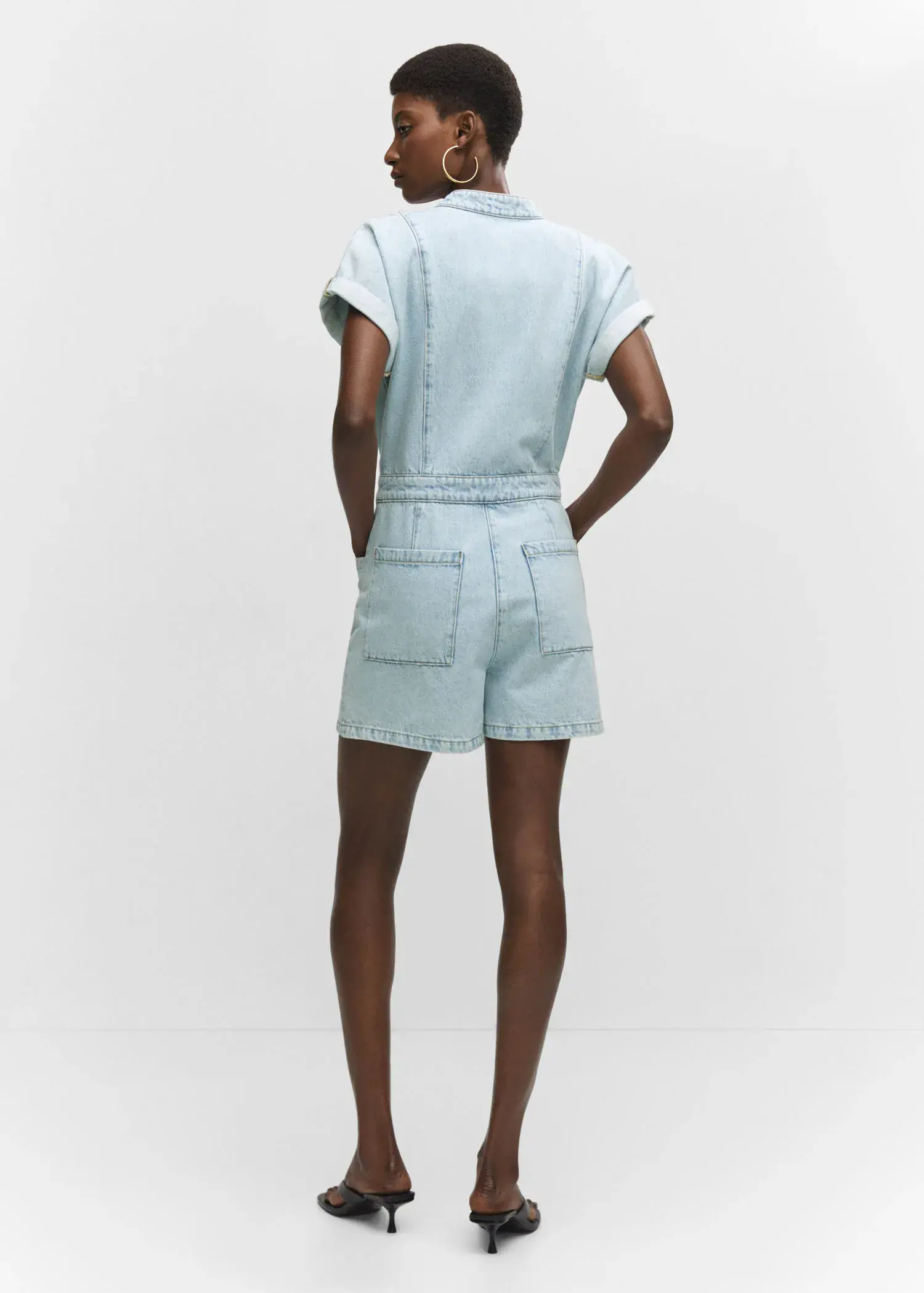 Mango Denim jumpsuit with pockets. a person wearing a light blue outfit standing in a room. 
