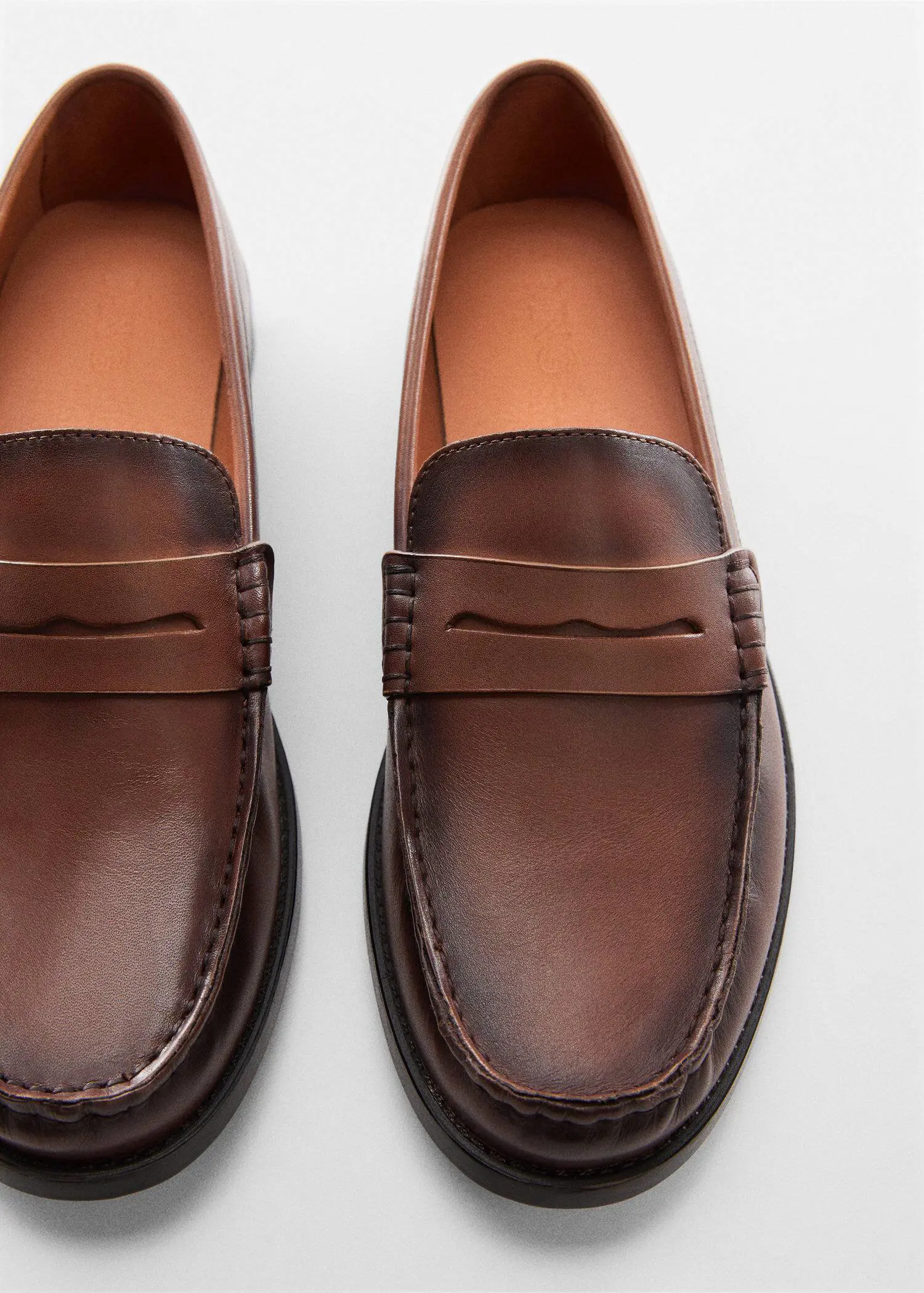 Mango Leather penny loafers. a close up of a pair of brown loafers. 