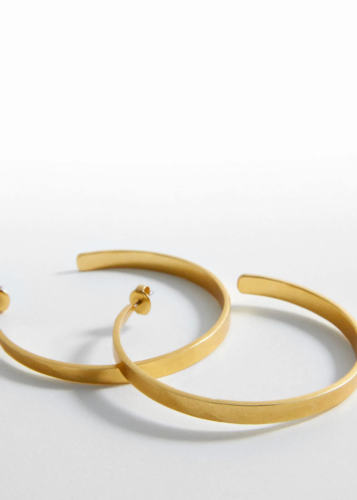 Mango Embossed hoop earrings. a close up of a pair of gold earrings 