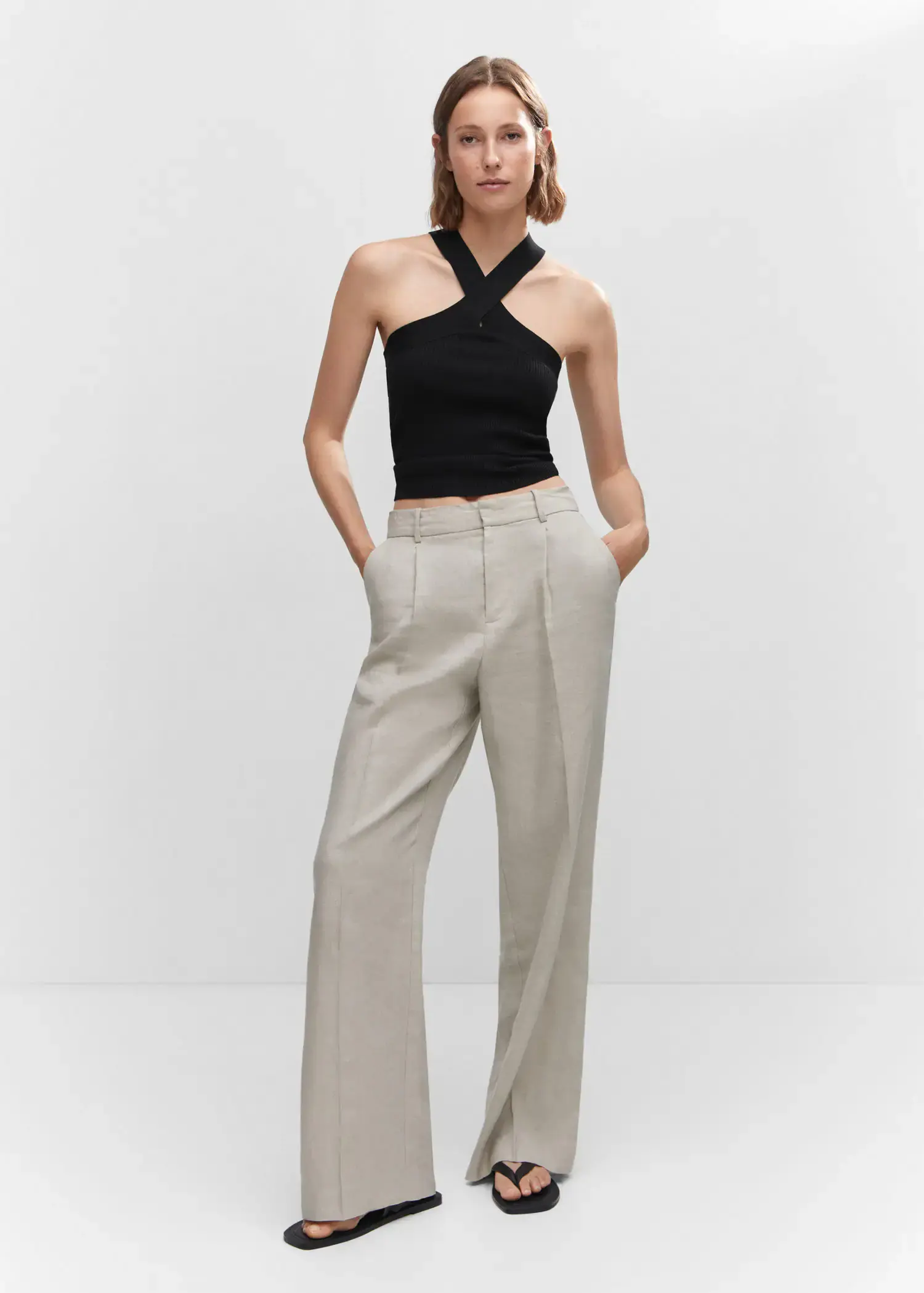 Mango Halter-neck knitted top. a woman in a black top and white pants. 