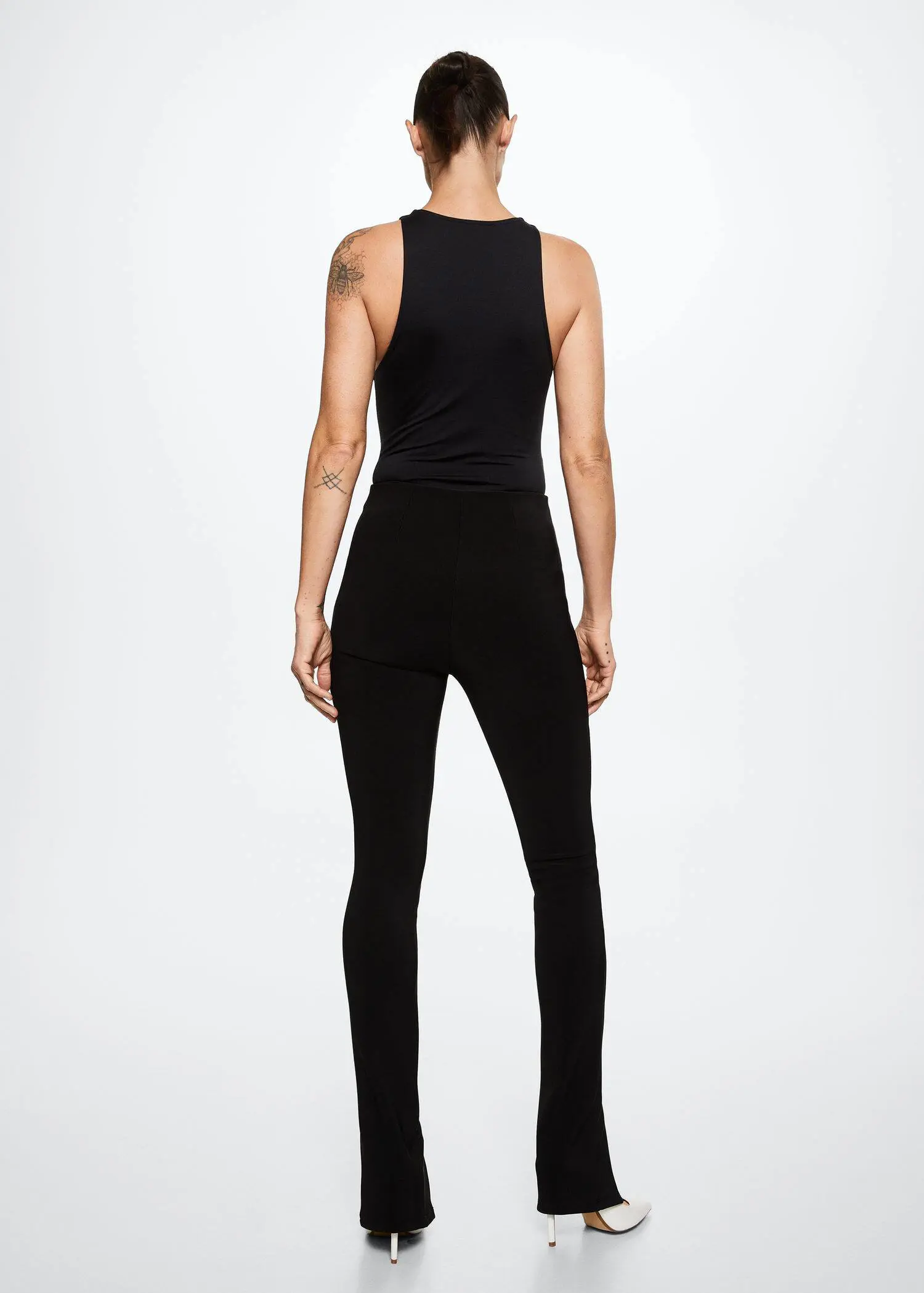 Mango Slit hem leggings. a person wearing a black outfit standing in a room. 