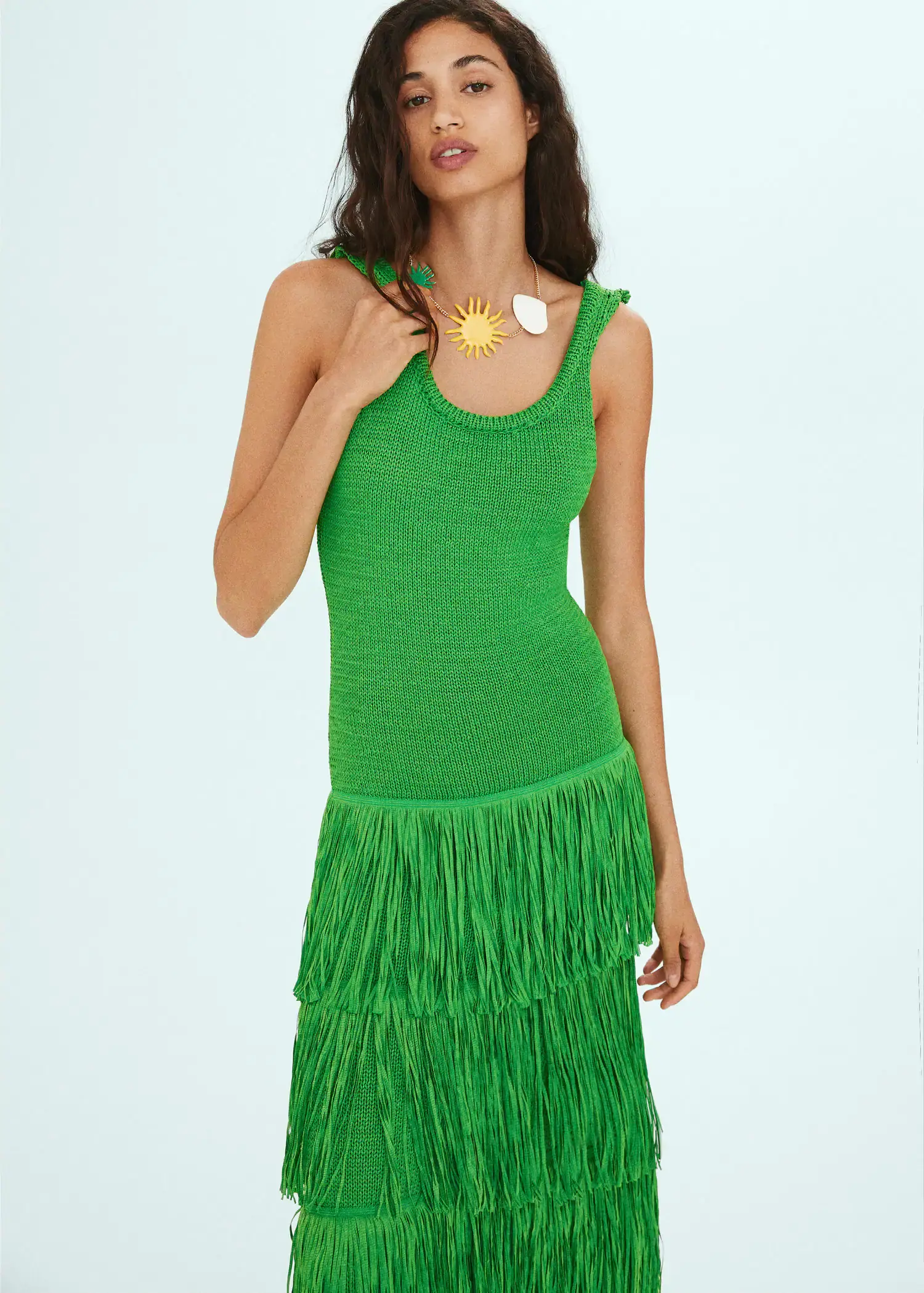 Mango Knitted dress with fringe design. a woman in a green dress holding a necklace. 
