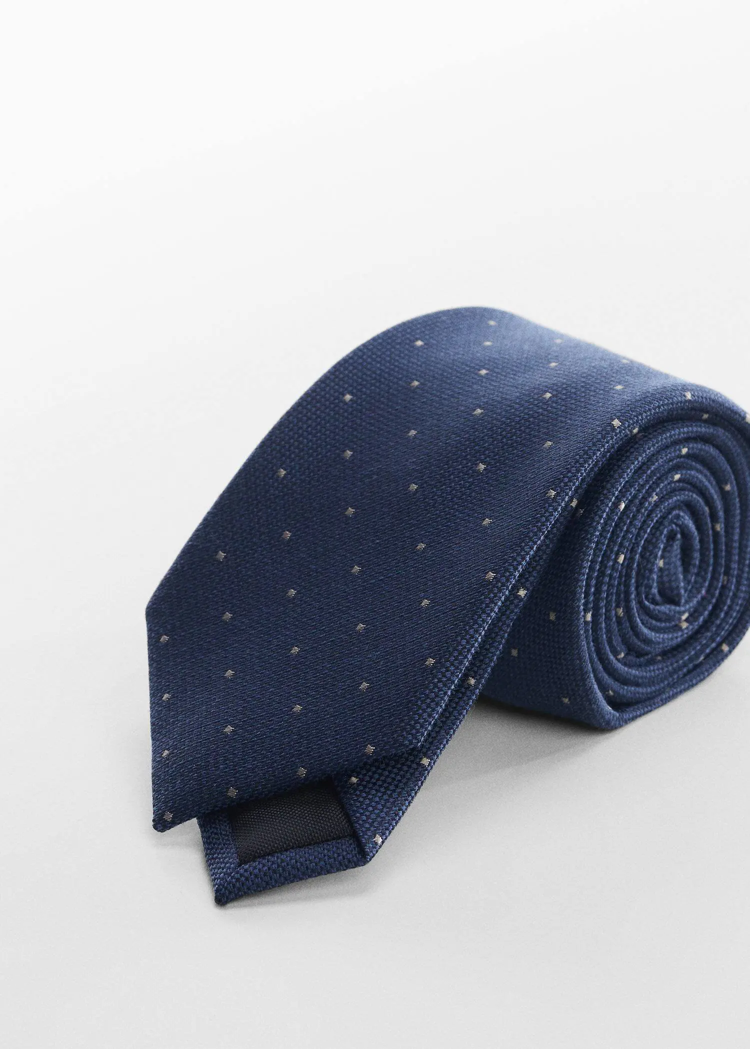 Mango Tie with micro polka-dot structure. a blue neck tie on top of a table. 