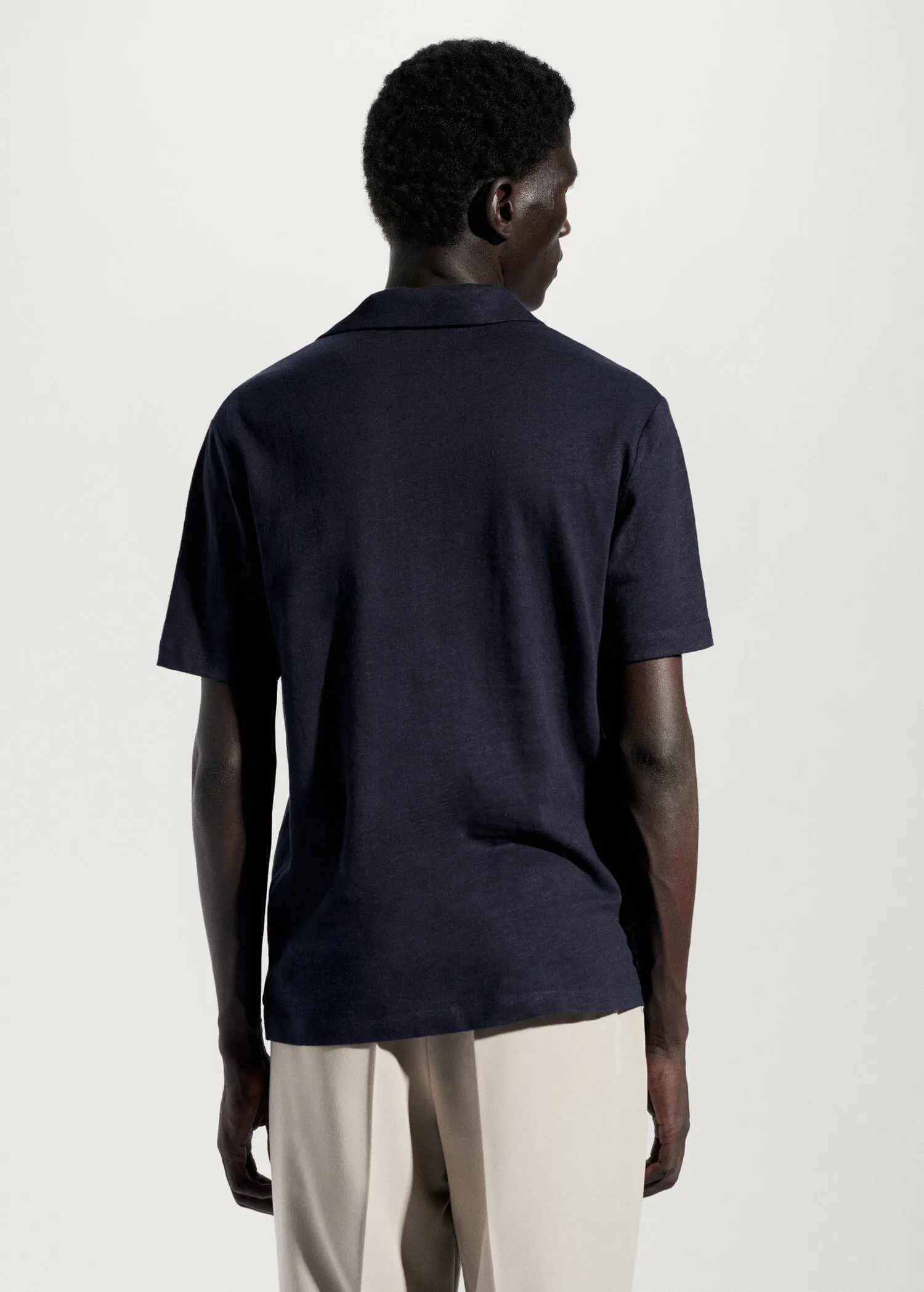 Mango Cotton linen slim-fit polo shirt. a man in a black shirt is standing in front of a white wall. 