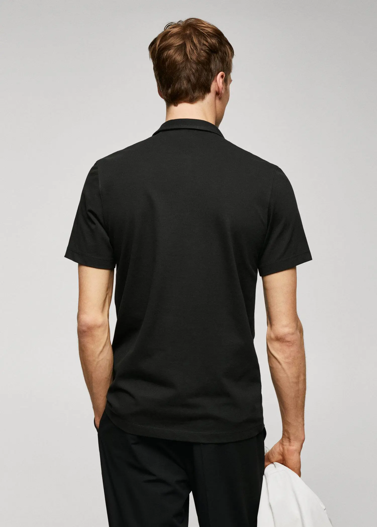 Mango Slim-fit textured cotton polo shirt. a man in a black shirt is standing with his hands in his pockets. 