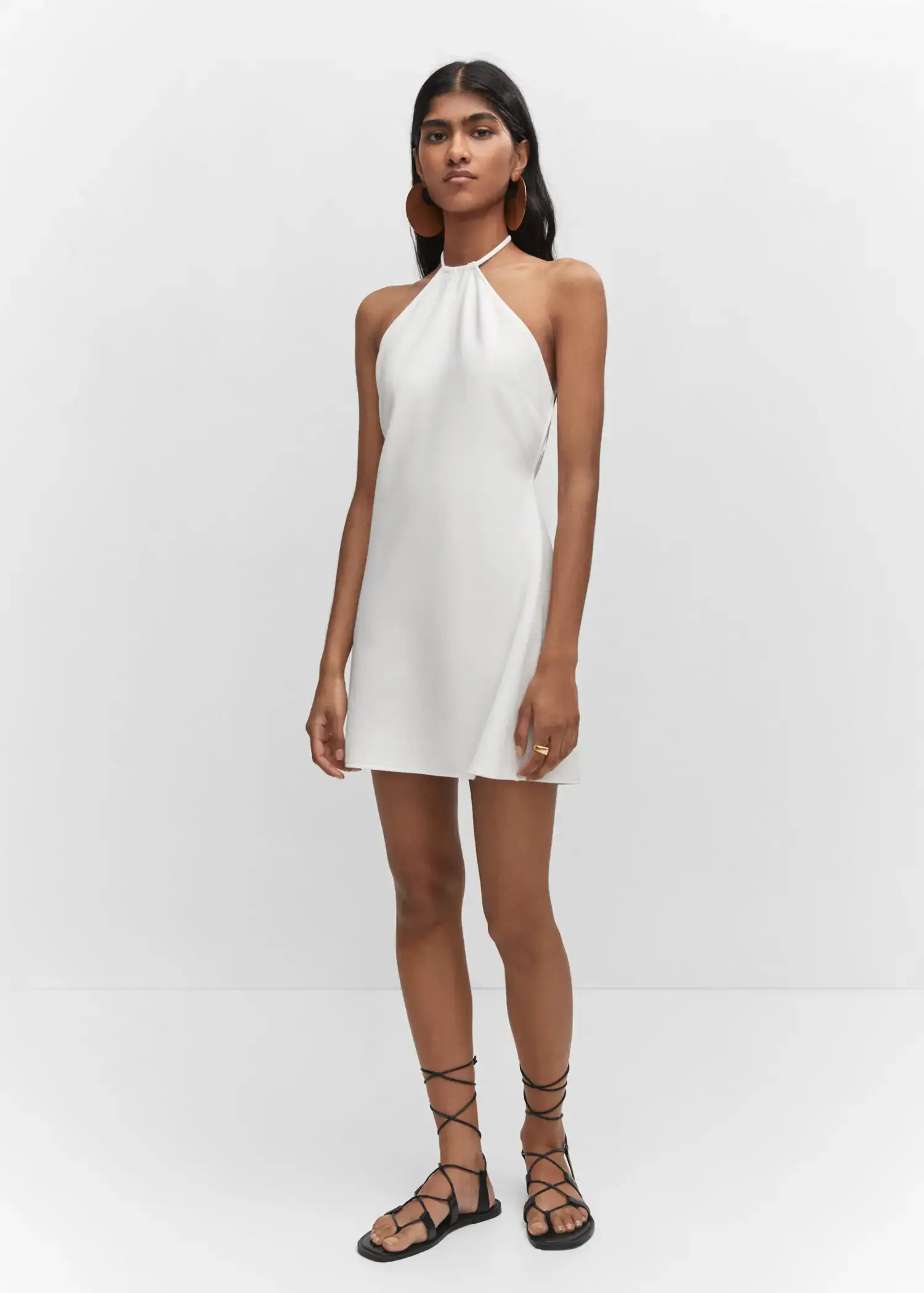 Mango Halter-neck dress with metal detail. a woman in a white dress standing in front of a white wall. 
