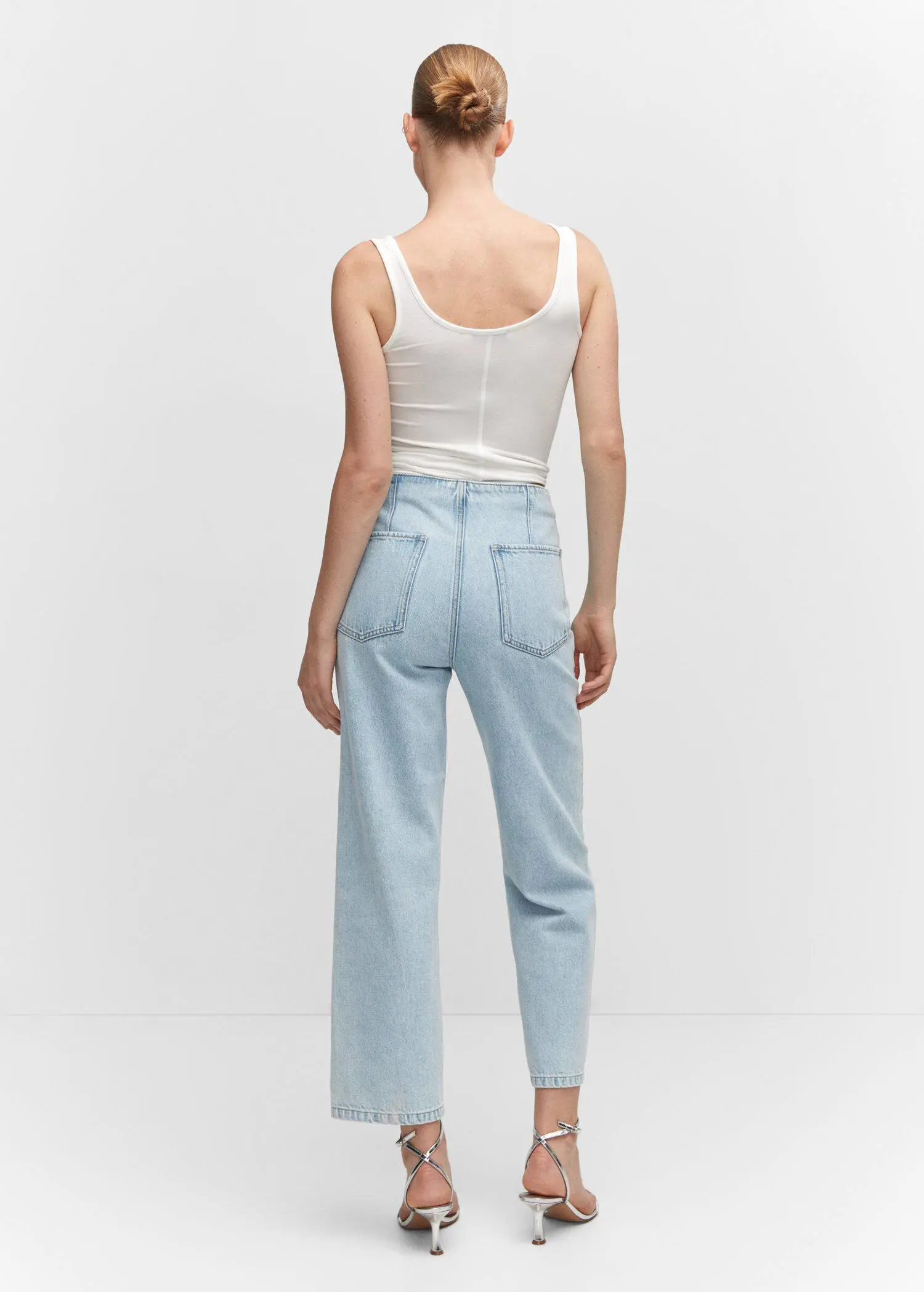 Mango Cropped straight-leg jeans with buttons. a woman wearing light blue jeans and a white tank top. 