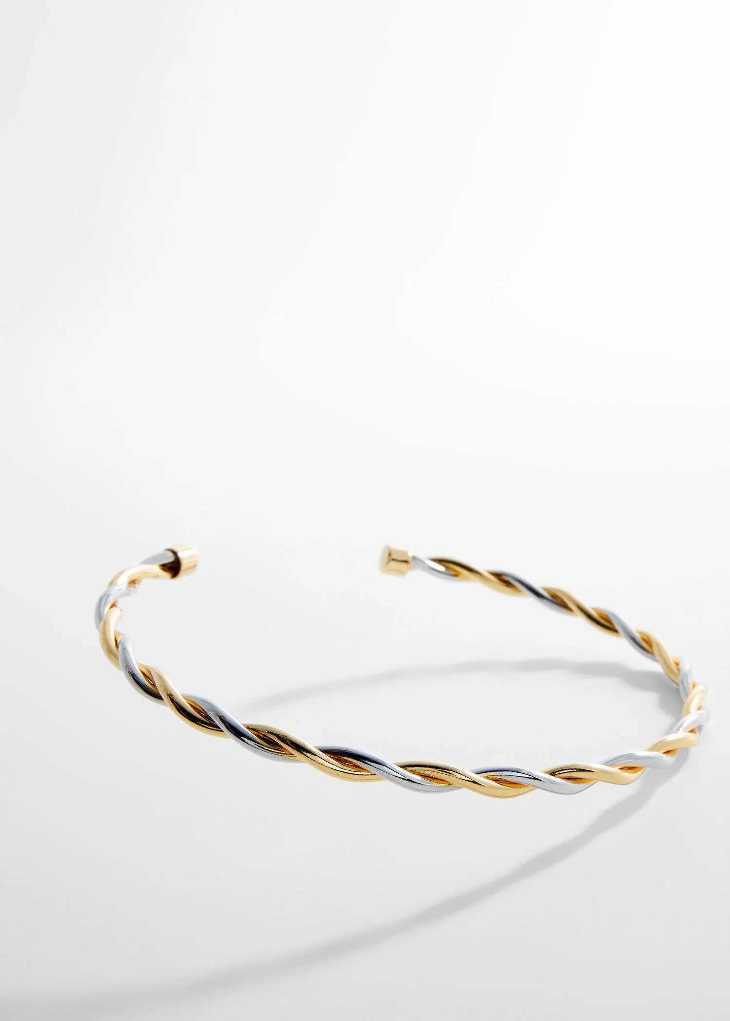 Mango Criss-cross rigid necklace. a close-up of a silver and gold bracelet. 