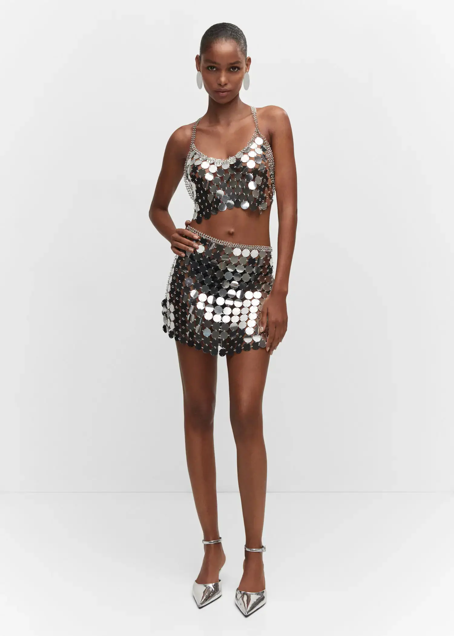 Mango Top metallic discs. a woman in a silver skirt and top. 