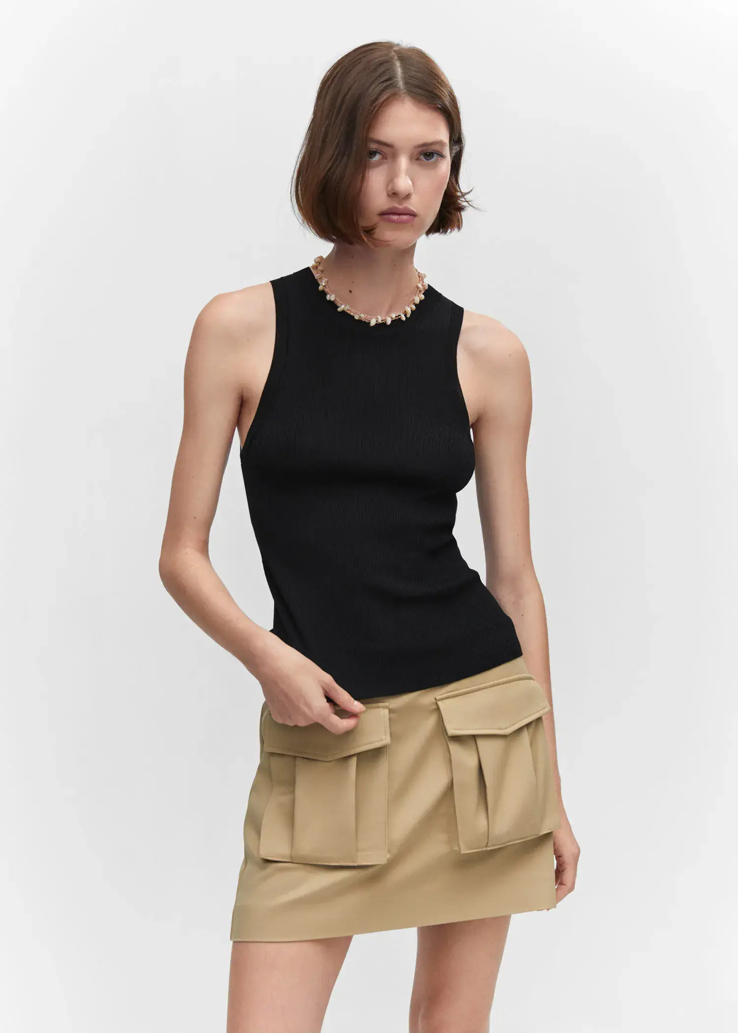 Mango Ribbed knit top. a woman wearing a black top and a tan skirt. 
