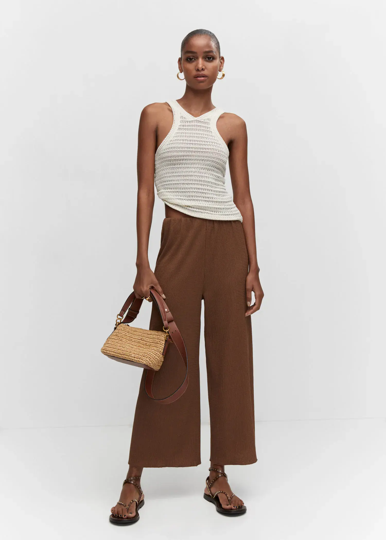 Mango Textured culotte pants. a woman holding a straw bag while standing in a room. 