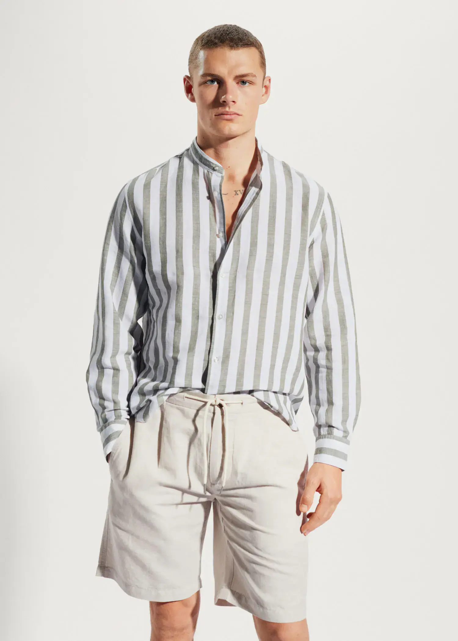 Mango Regular-fit striped linen shirt. a man wearing a striped shirt and white shorts. 