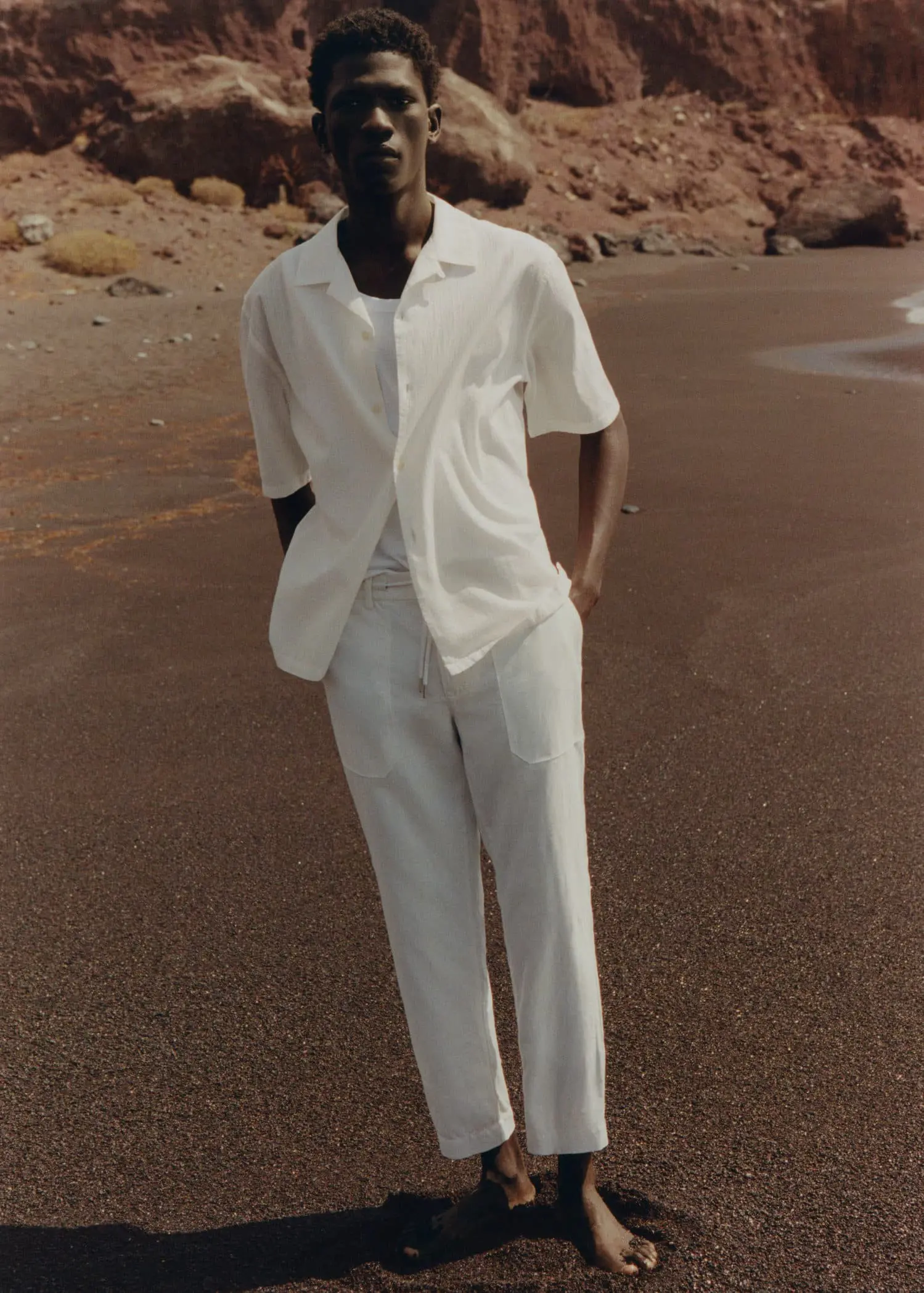 Mango Regular fit cotton linen trousers. a man standing on the beach wearing a white suit. 