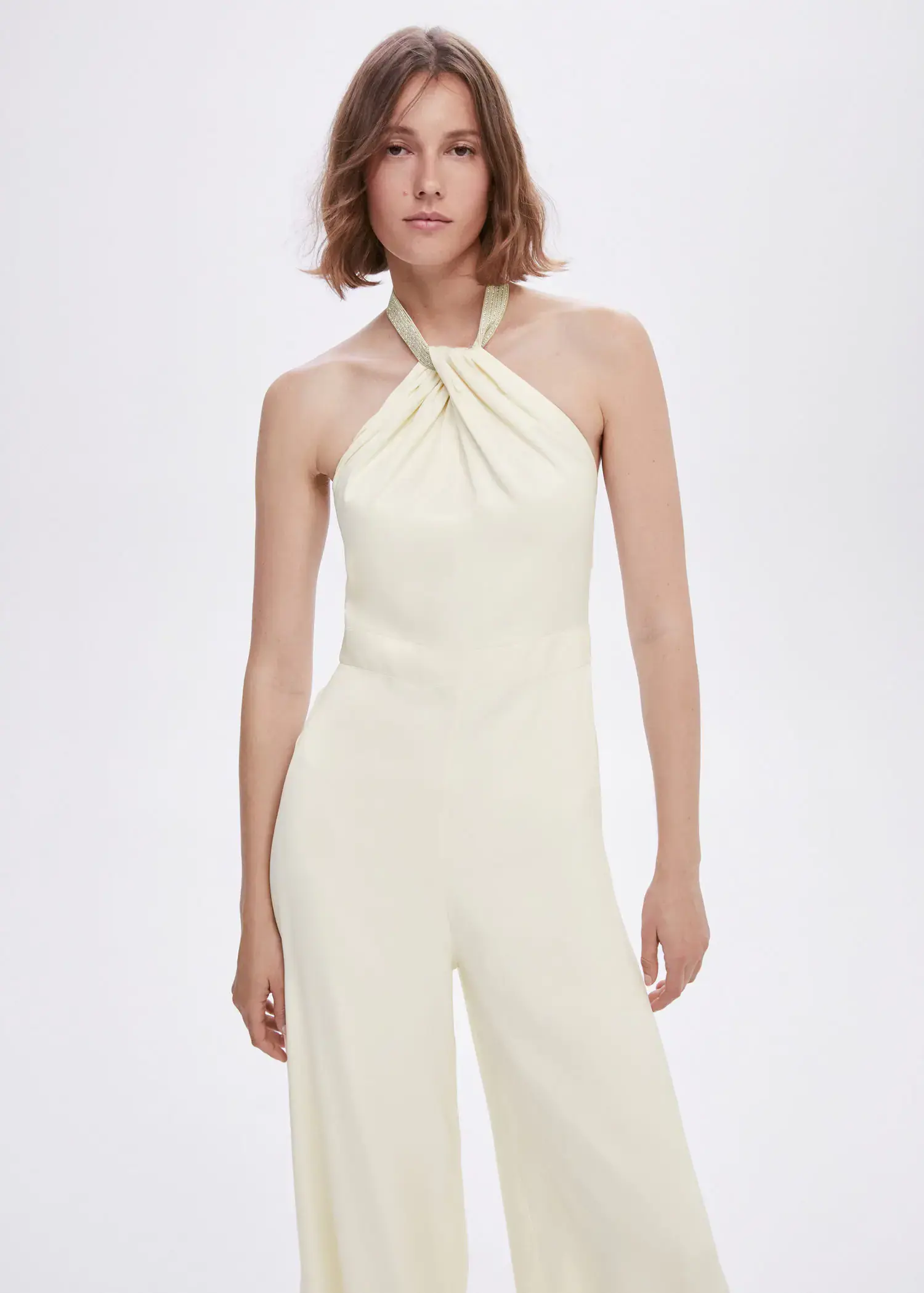 Mango Halter-neck jumpsuit with metallic detail. a woman in a white jumpsuit is posing for a picture. 