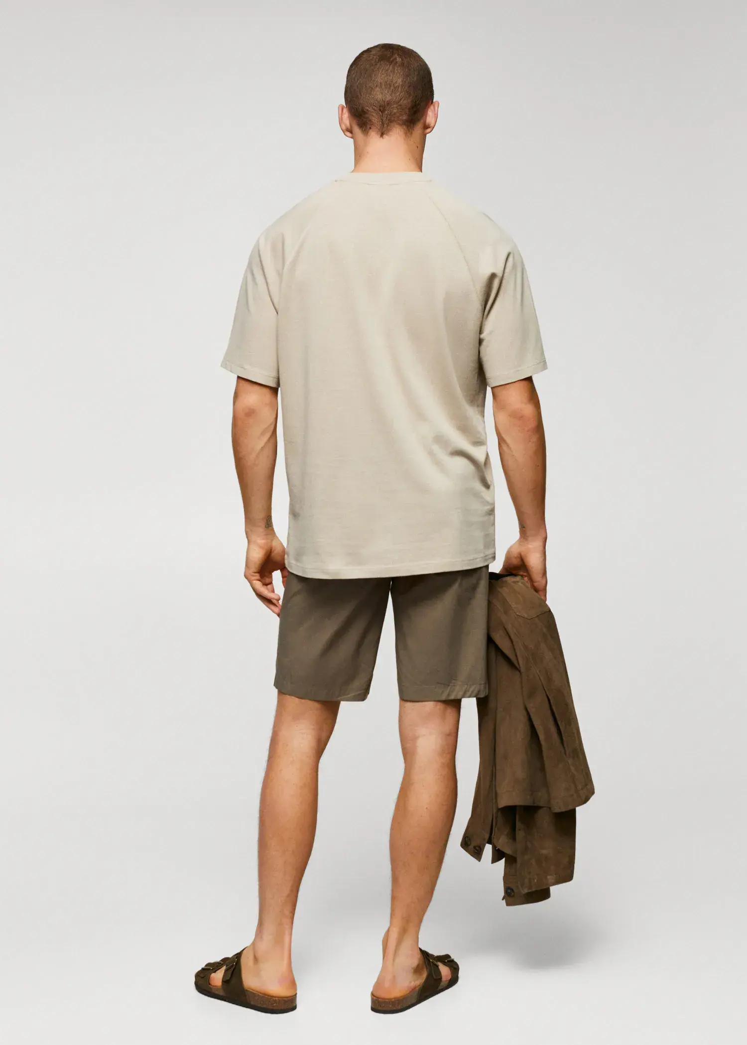 Mango Textured cotton-linen t-shirt. a man in shorts and a t-shirt is holding a jacket. 