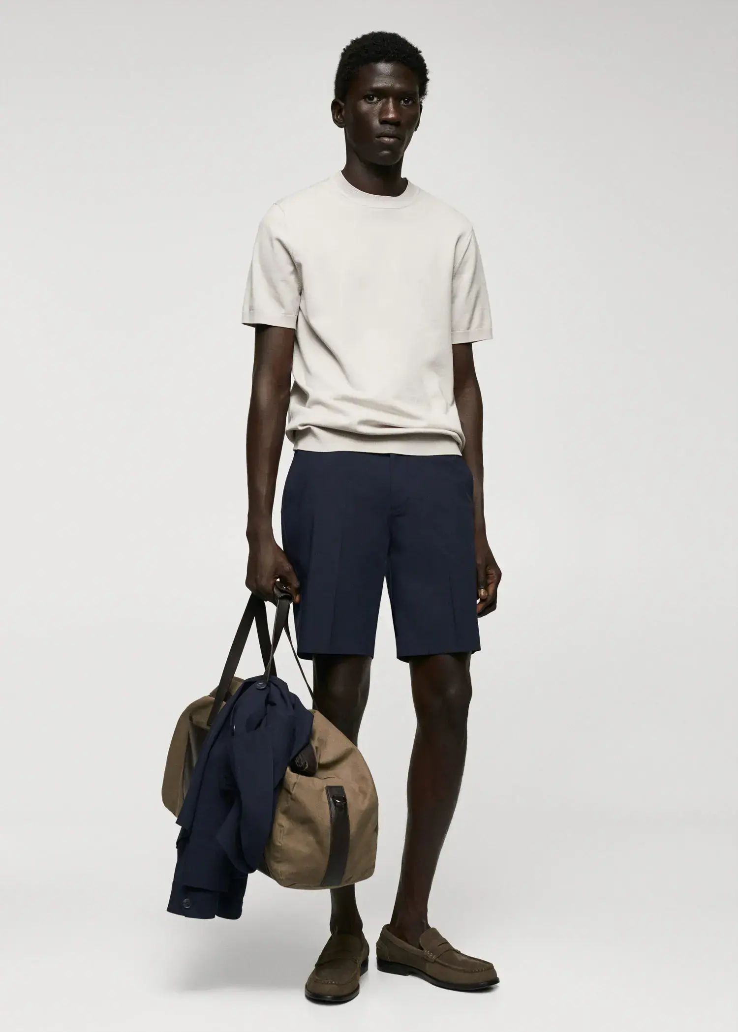 Mango Slim-fit bermuda shorts with adjustable waist. a man holding a bag in front of a wall. 