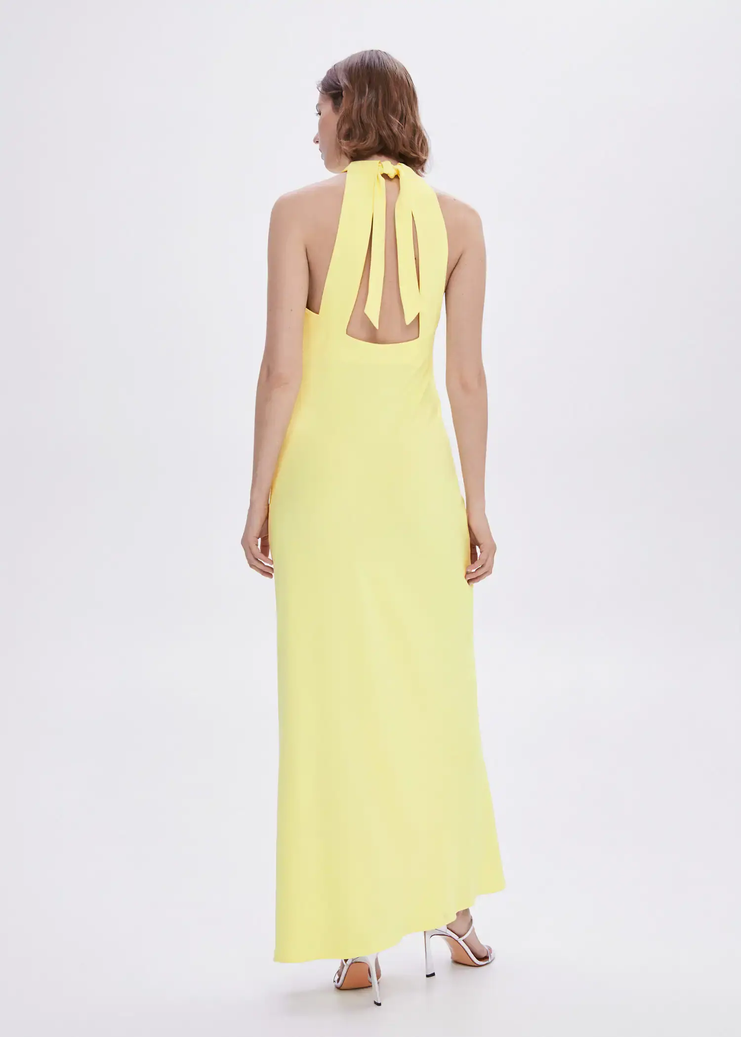 Mango Halter-neck open-back dress. a woman wearing a yellow dress standing in front of a white wall. 
