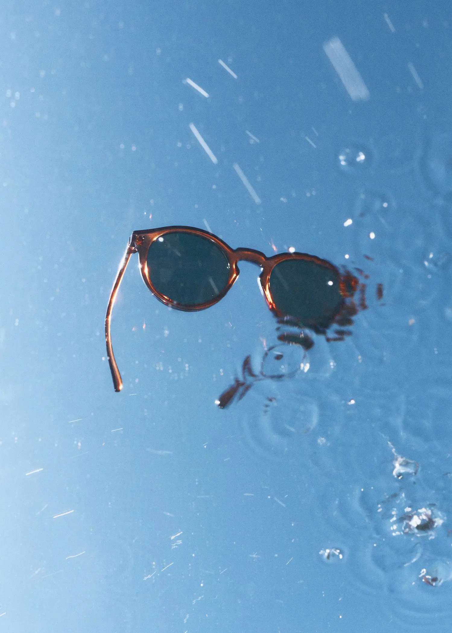 Mango Rounded sunglasses. a pair of sunglasses sitting on top of a puddle of water. 