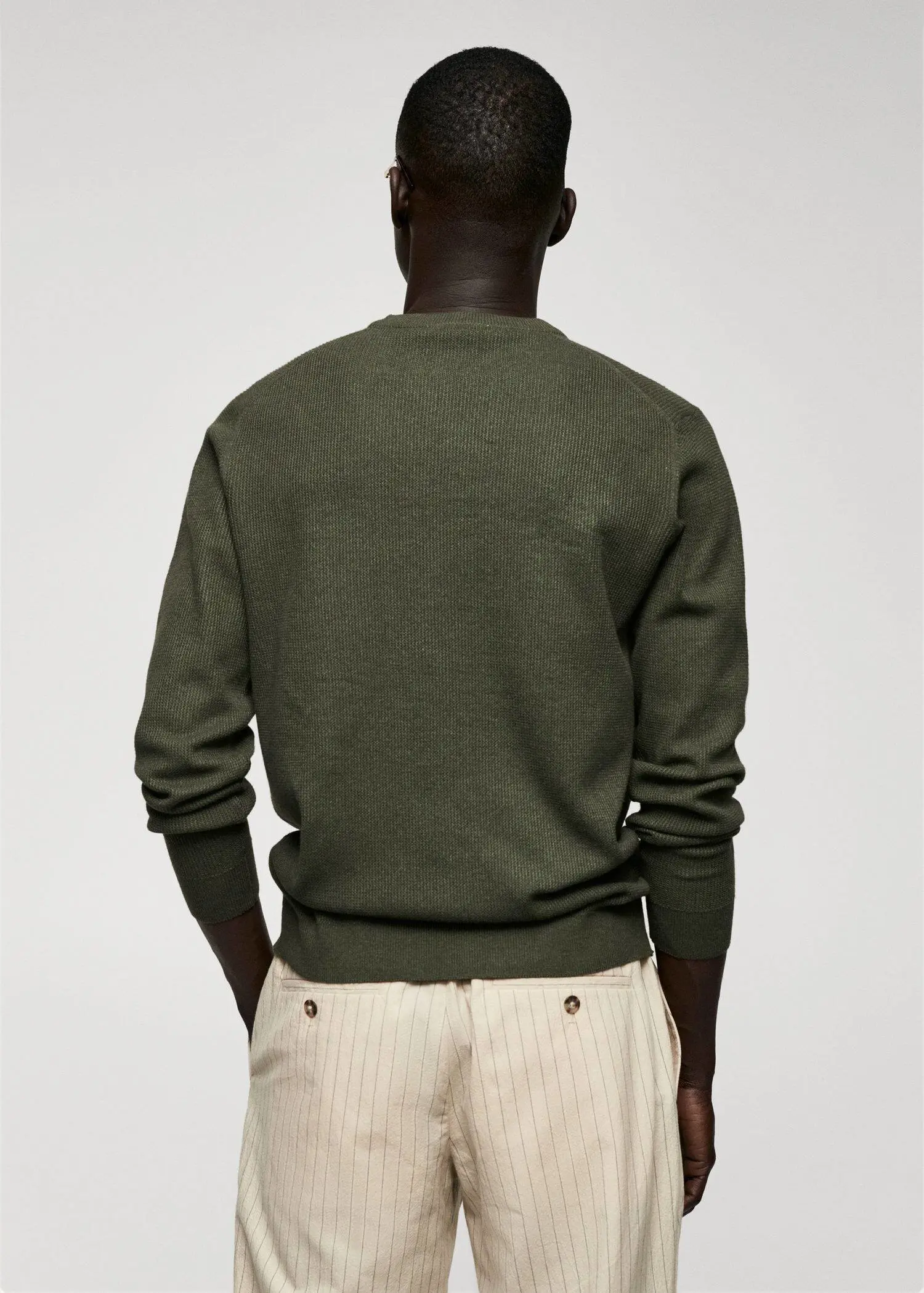 Mango Structured cotton sweater. a man wearing a green sweater and white pants. 