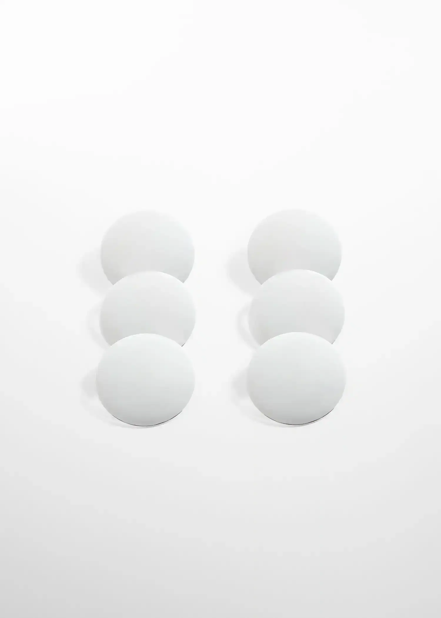 Mango Long earrings with circular design. a group of six white buttons sitting on top of a white surface. 