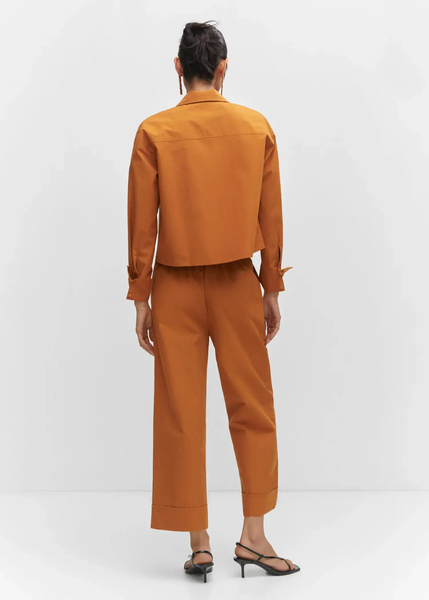 Mango Pleated culottes trousers. a person standing in front of a white wall. 