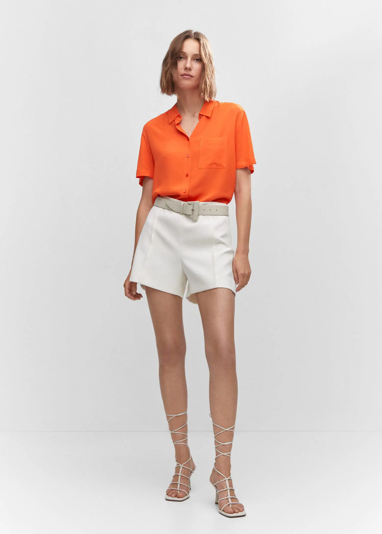 Mango Pocket oversize shirt. a woman in a white skirt and orange shirt. 