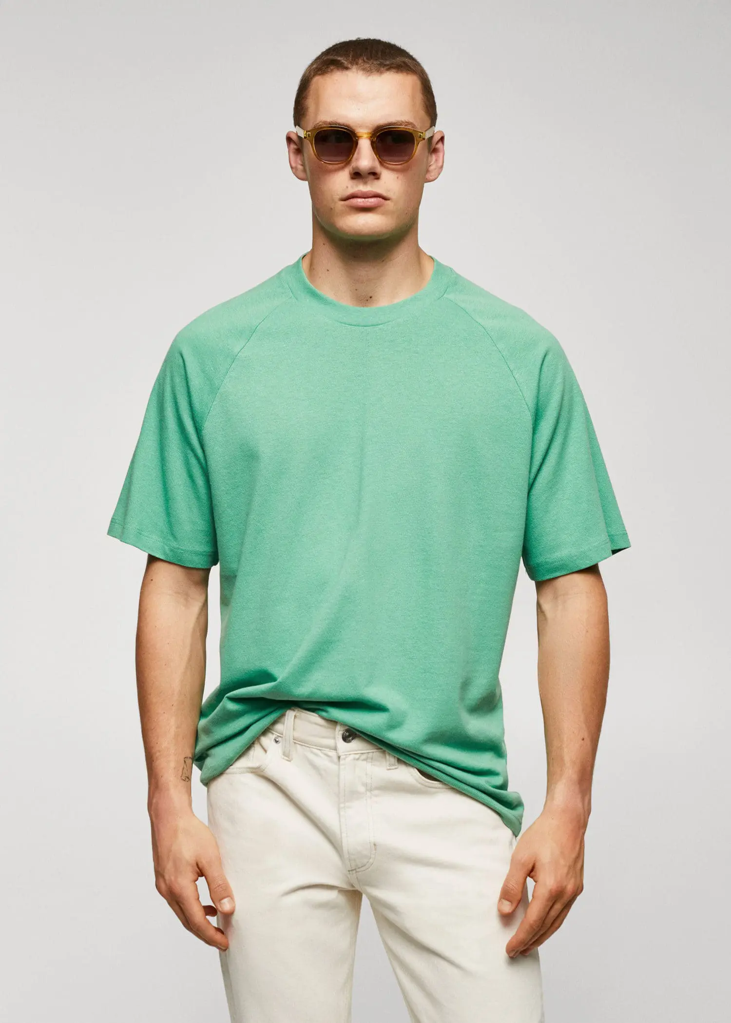 Mango Textured cotton-linen t-shirt. a man in a green shirt and white pants. 