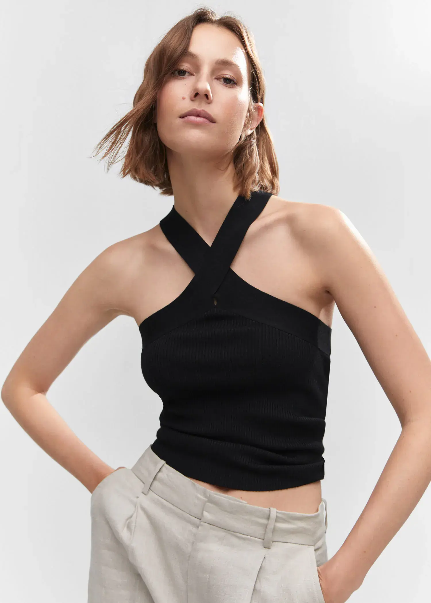 Mango Halter-neck knitted top. a woman wearing a black halter top posing for a picture. 