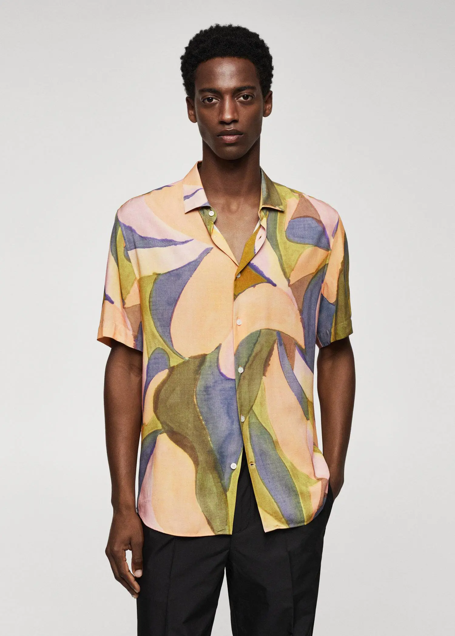Mango Printed short-sleeved shirt. a man wearing a colorful shirt standing in front of a white wall. 