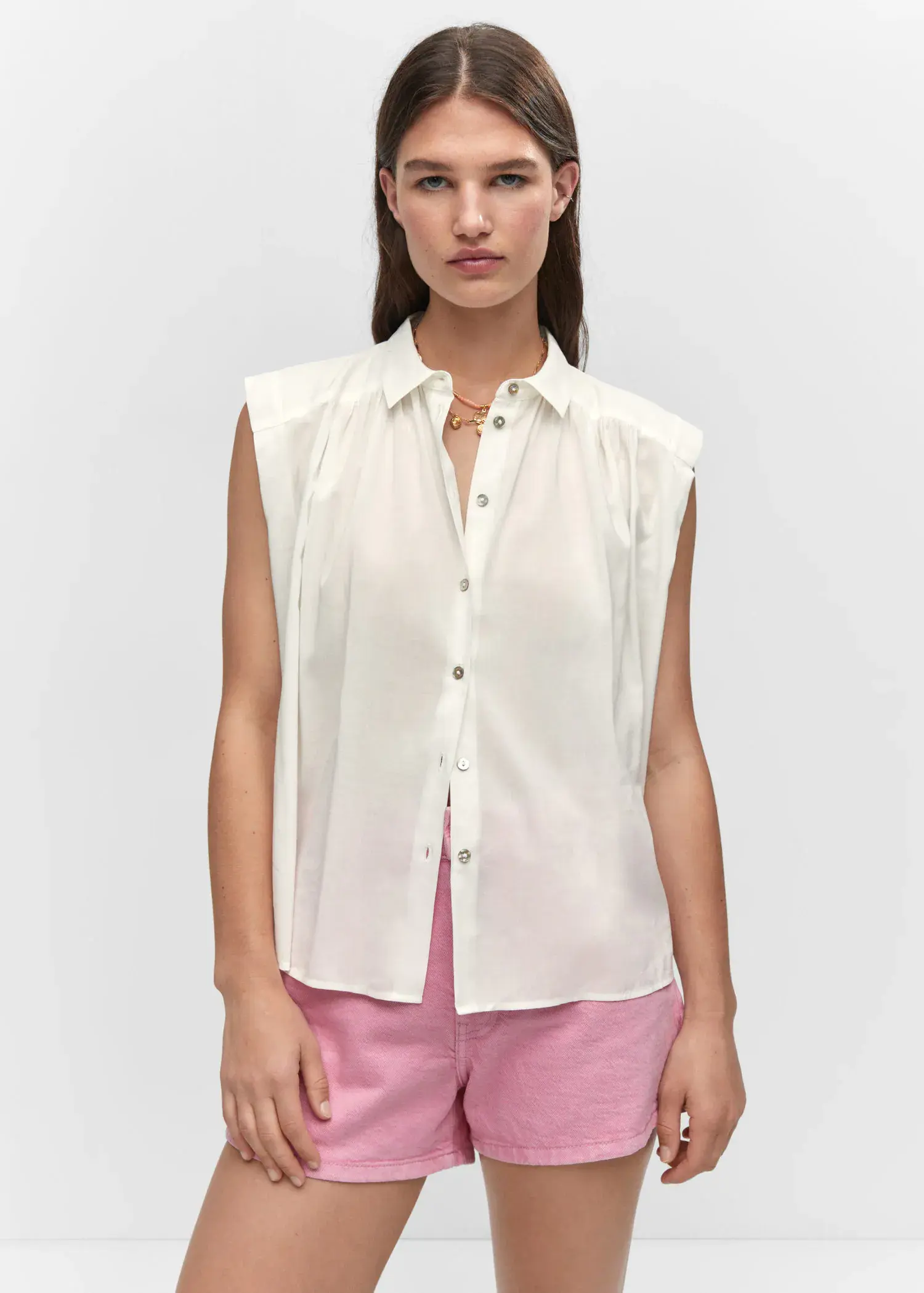 Mango Sleeveless button-down shirt. a woman wearing a white shirt and pink pants. 