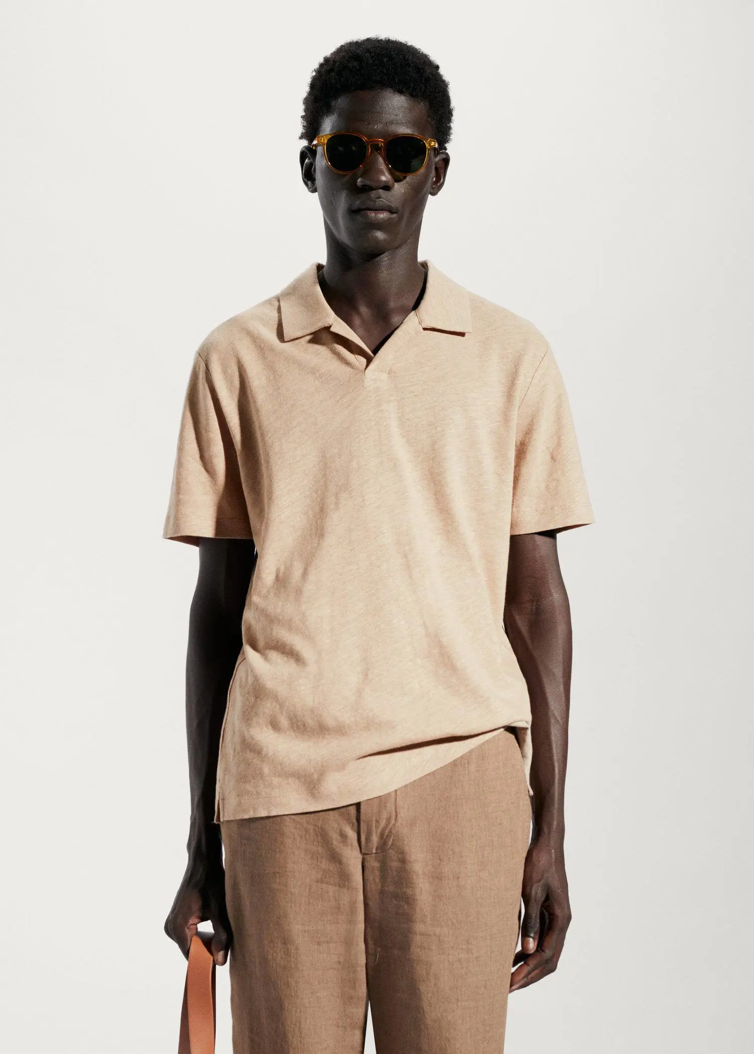 Mango Cotton linen slim-fit polo shirt. a man in a tan polo shirt stands in front of a wall. 