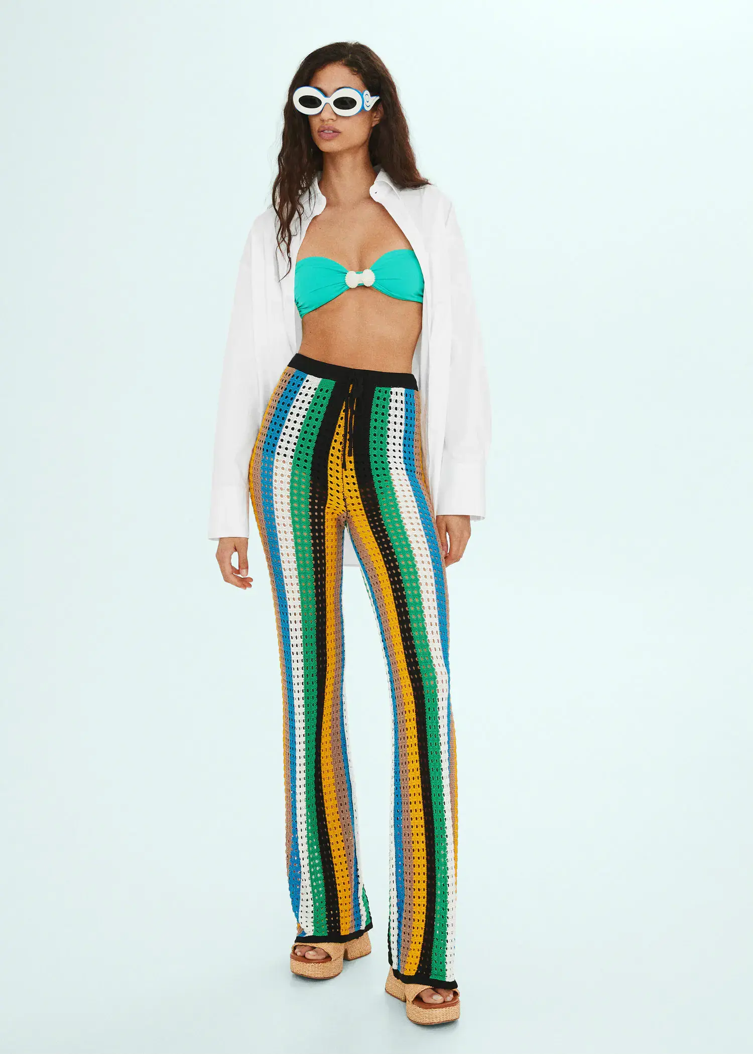 Mango Openwork knit pants. a woman wearing a white jacket and a colorful outfit. 