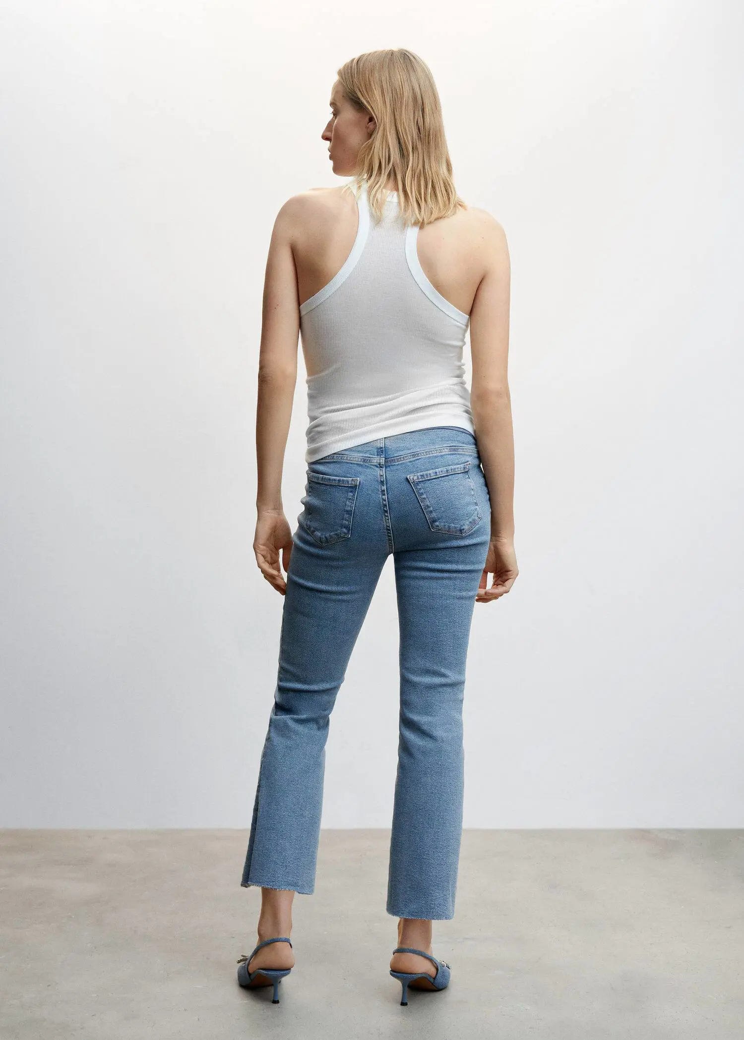 Mango Maternity flared cropped jeans. a woman wearing a white tank top and jeans. 
